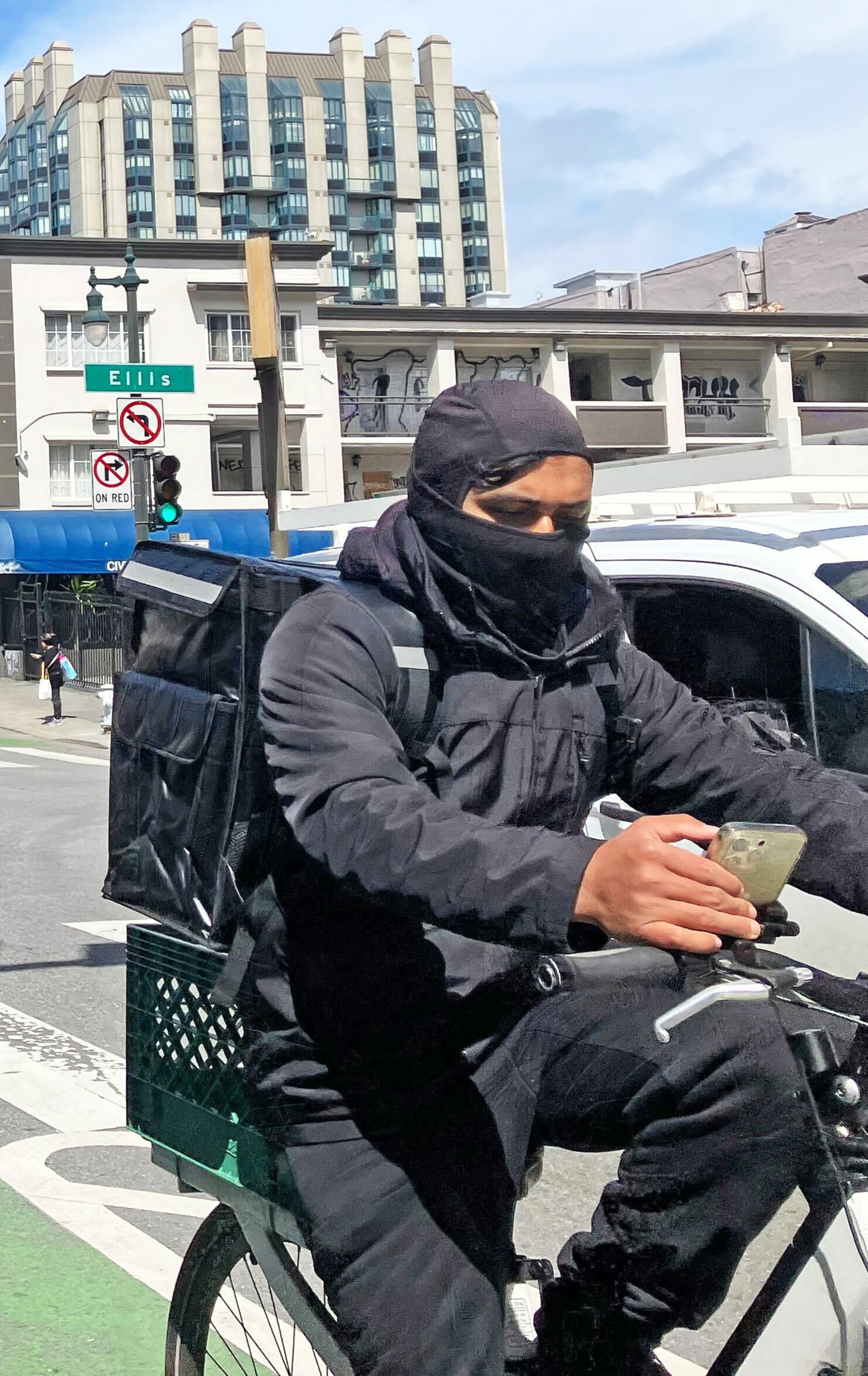 A man donning a 'shiesty' mask rides his bike near the corner of Ellis and Polk.