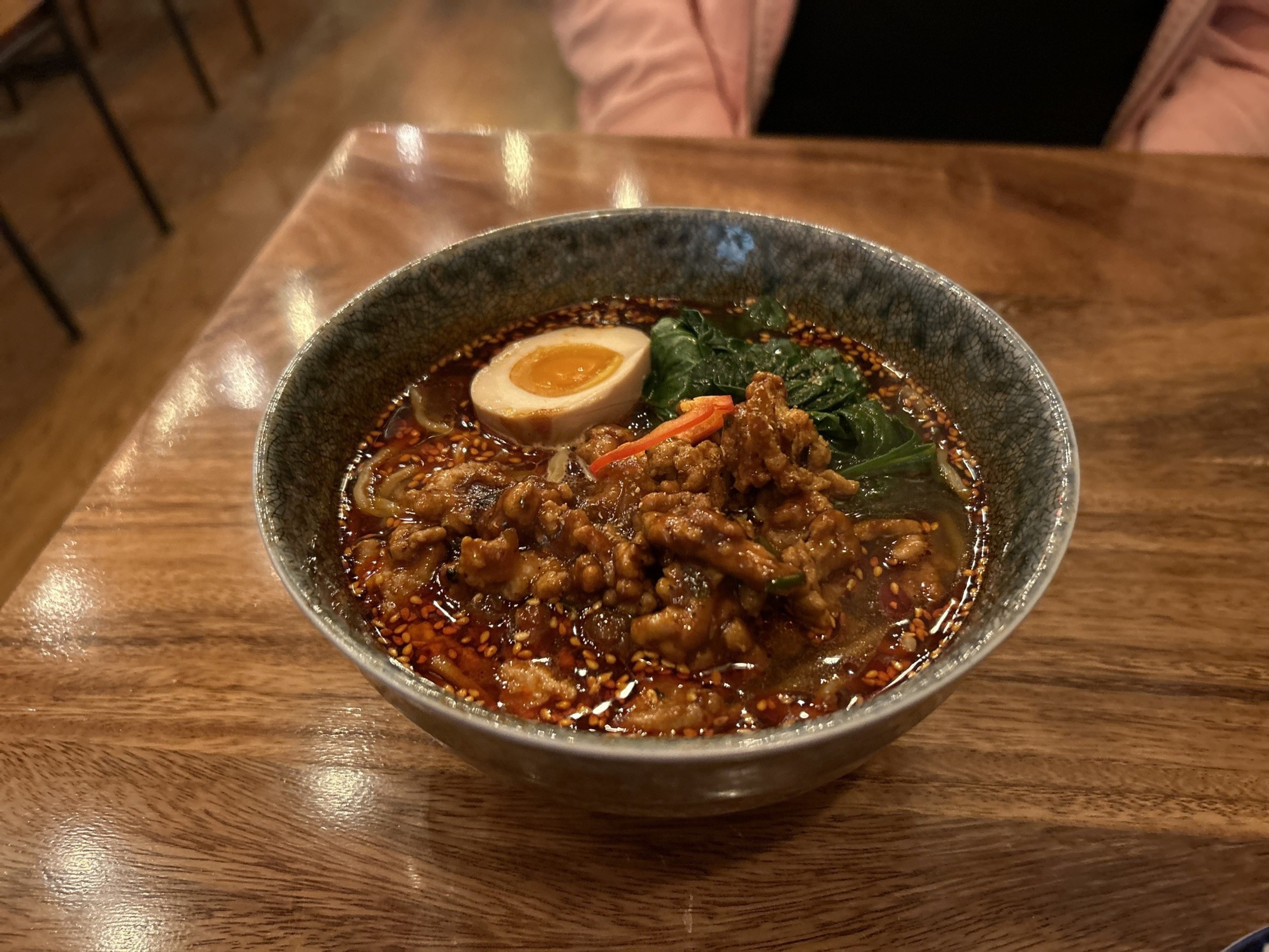 A bowl of meaty noodles in broth sits on a table.