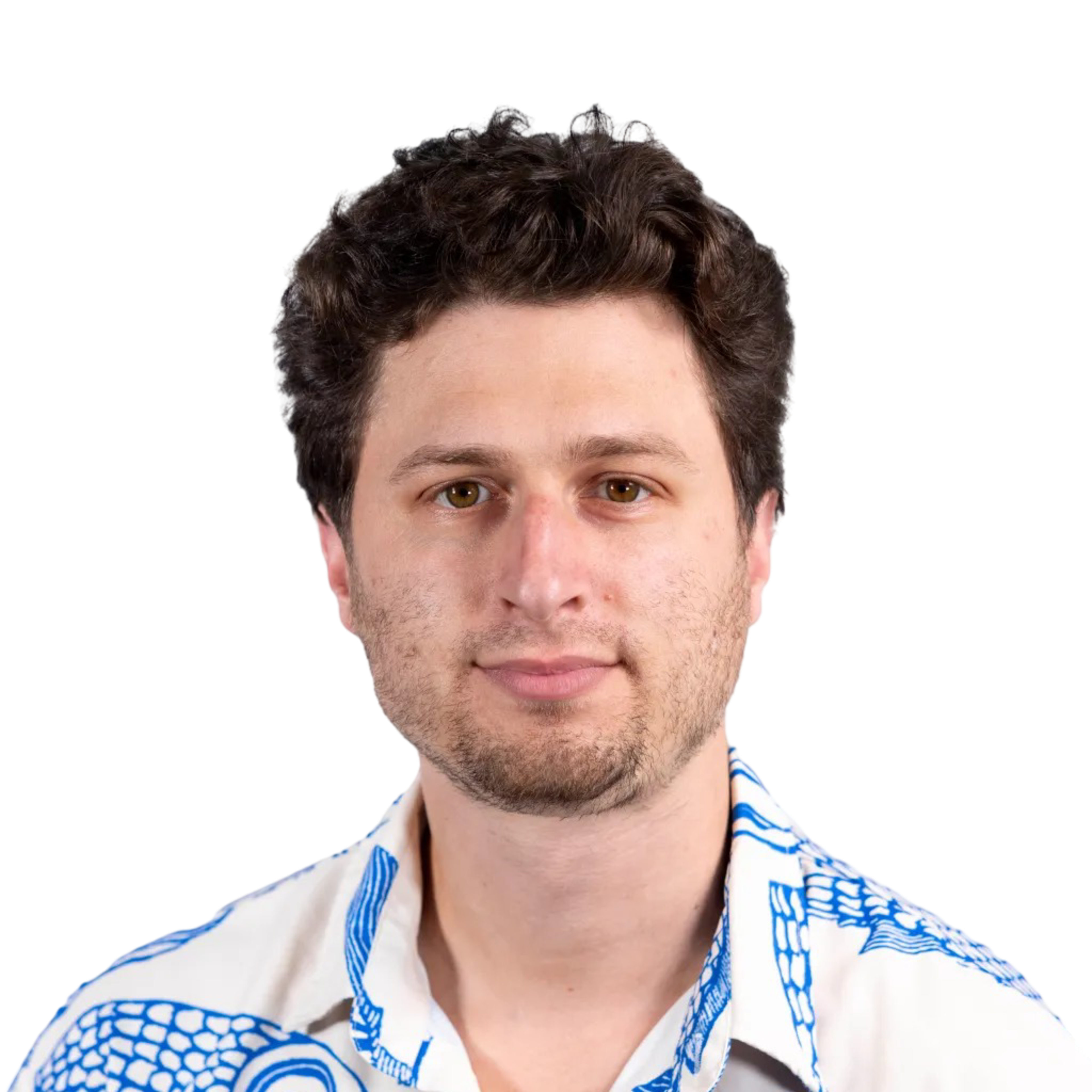 A man with curly dark hair and light facial hair wears a white shirt featuring large blue fish illustrations.