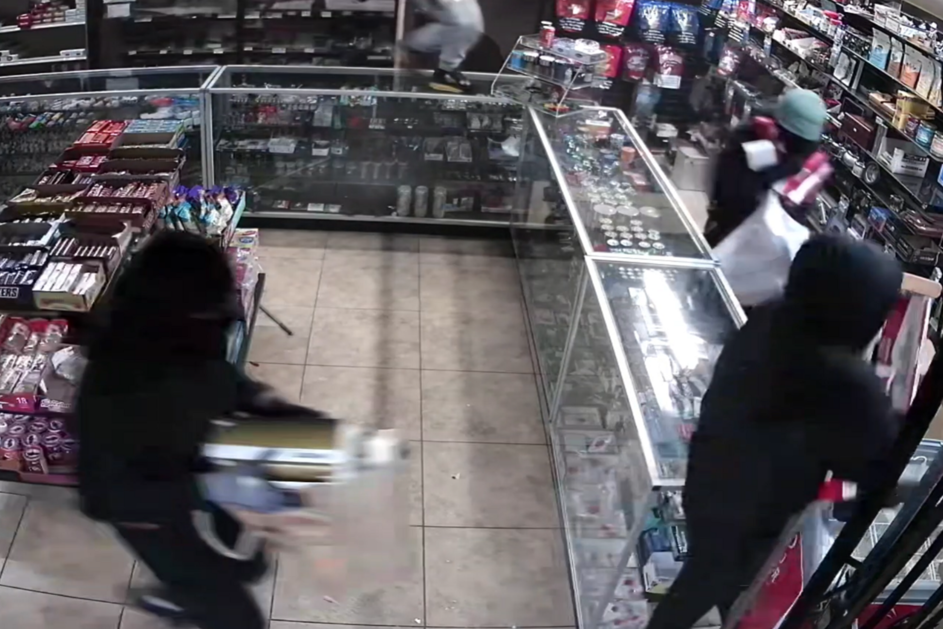 A still taken from surveillance video shows thieves ransacking a smoke shop.