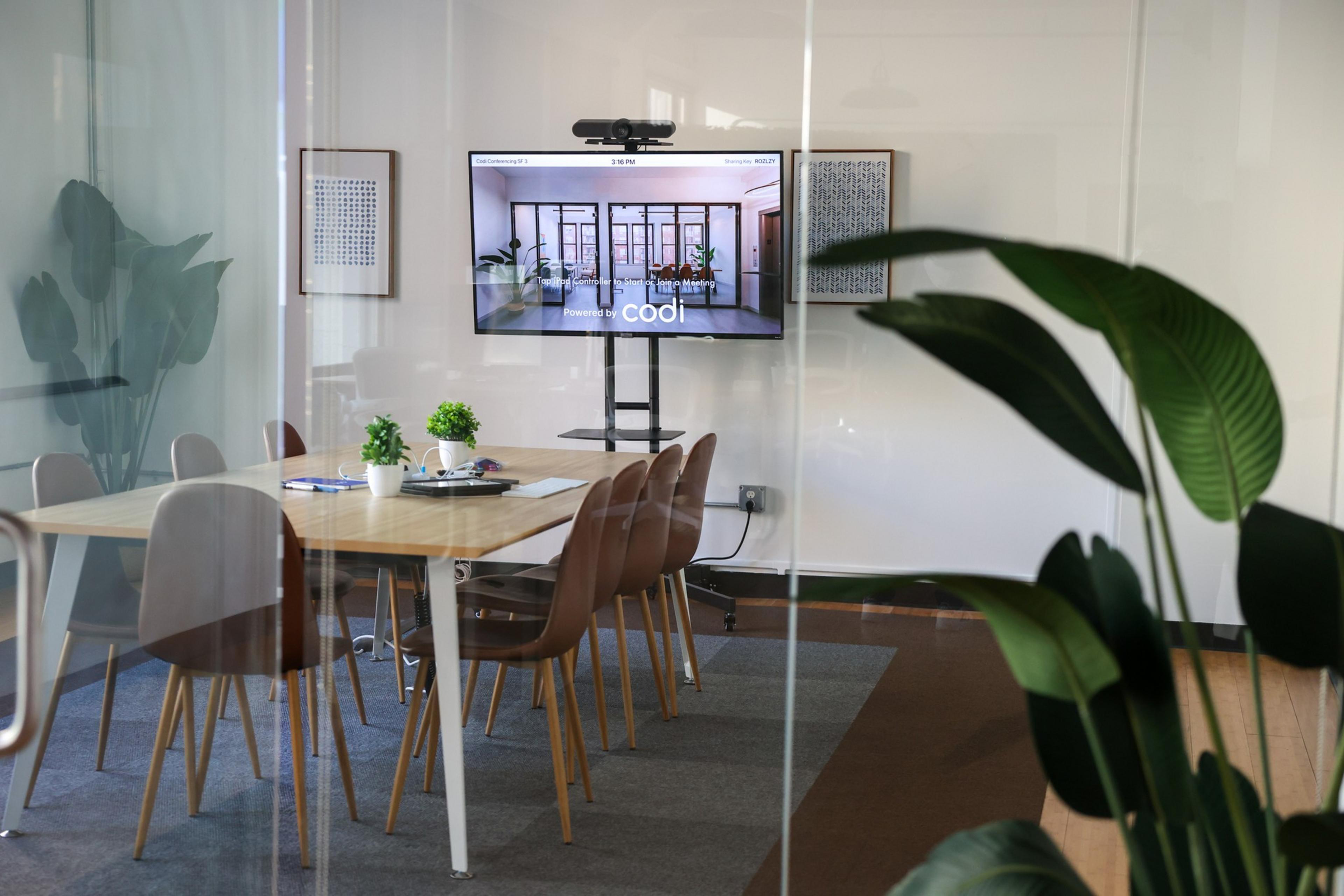 A conference room with a table chairs and a tv
