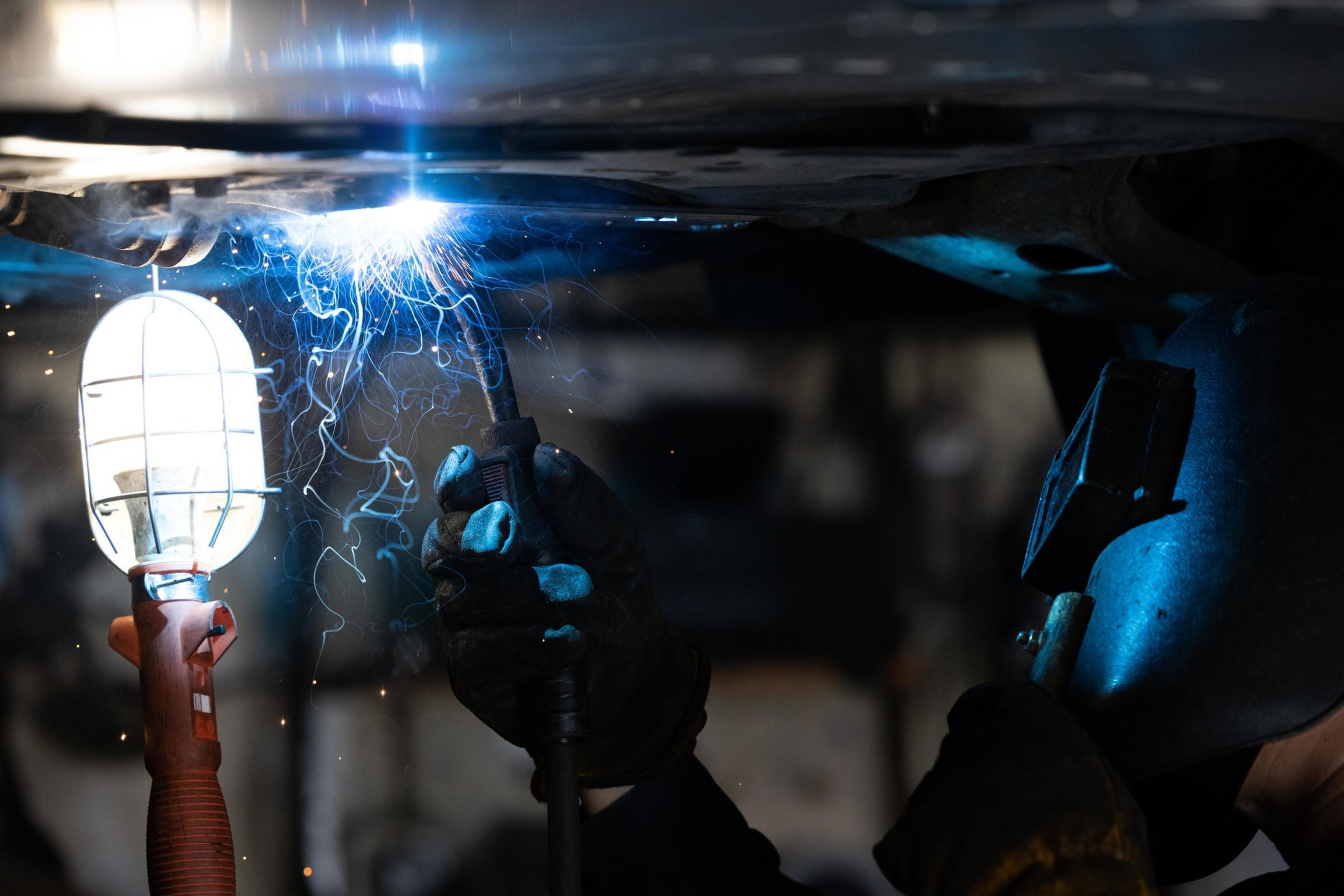A worker welds guards to protect a car's catalytic converter from theft.