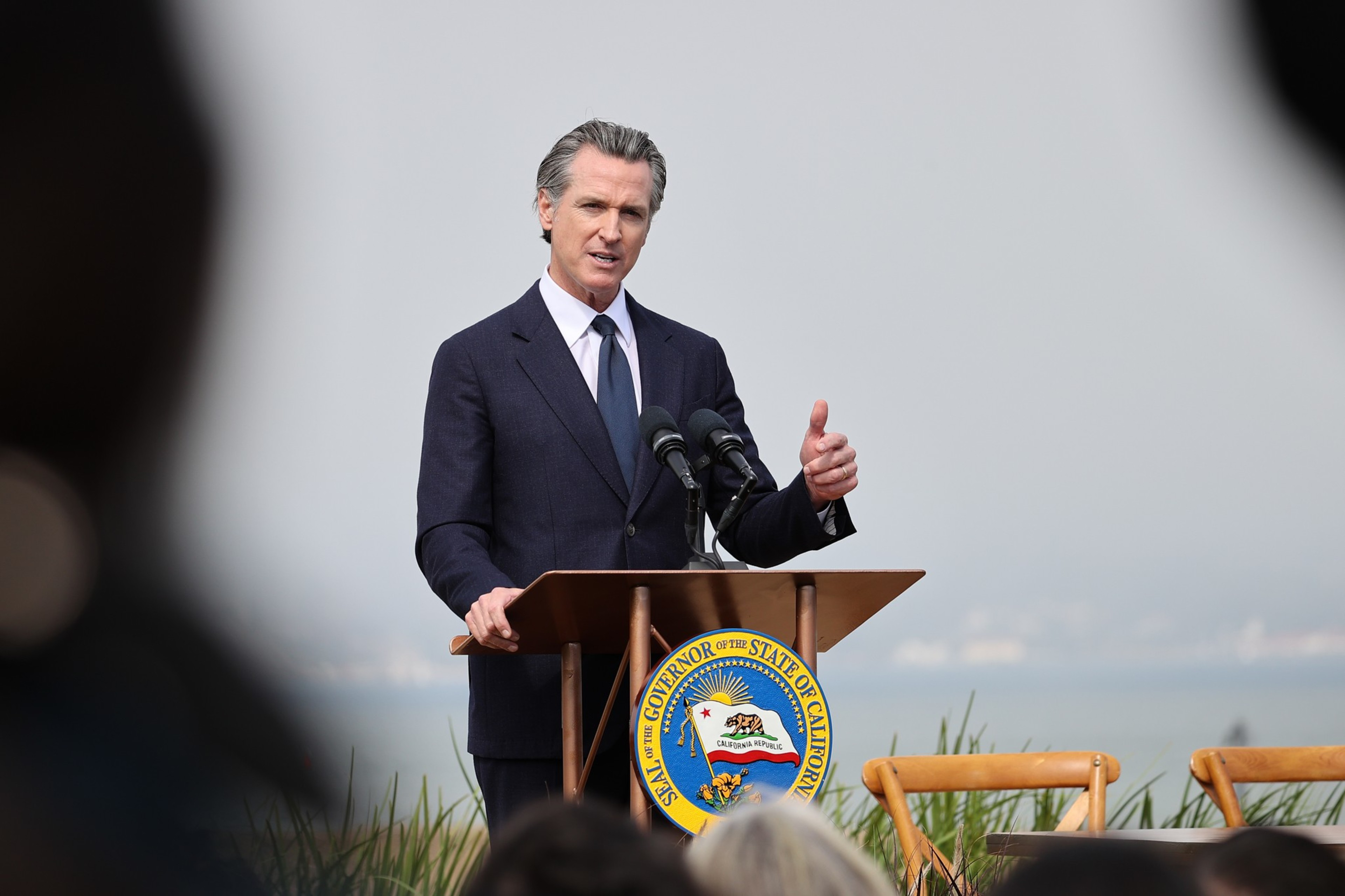A man in a suit talks behind a podium.