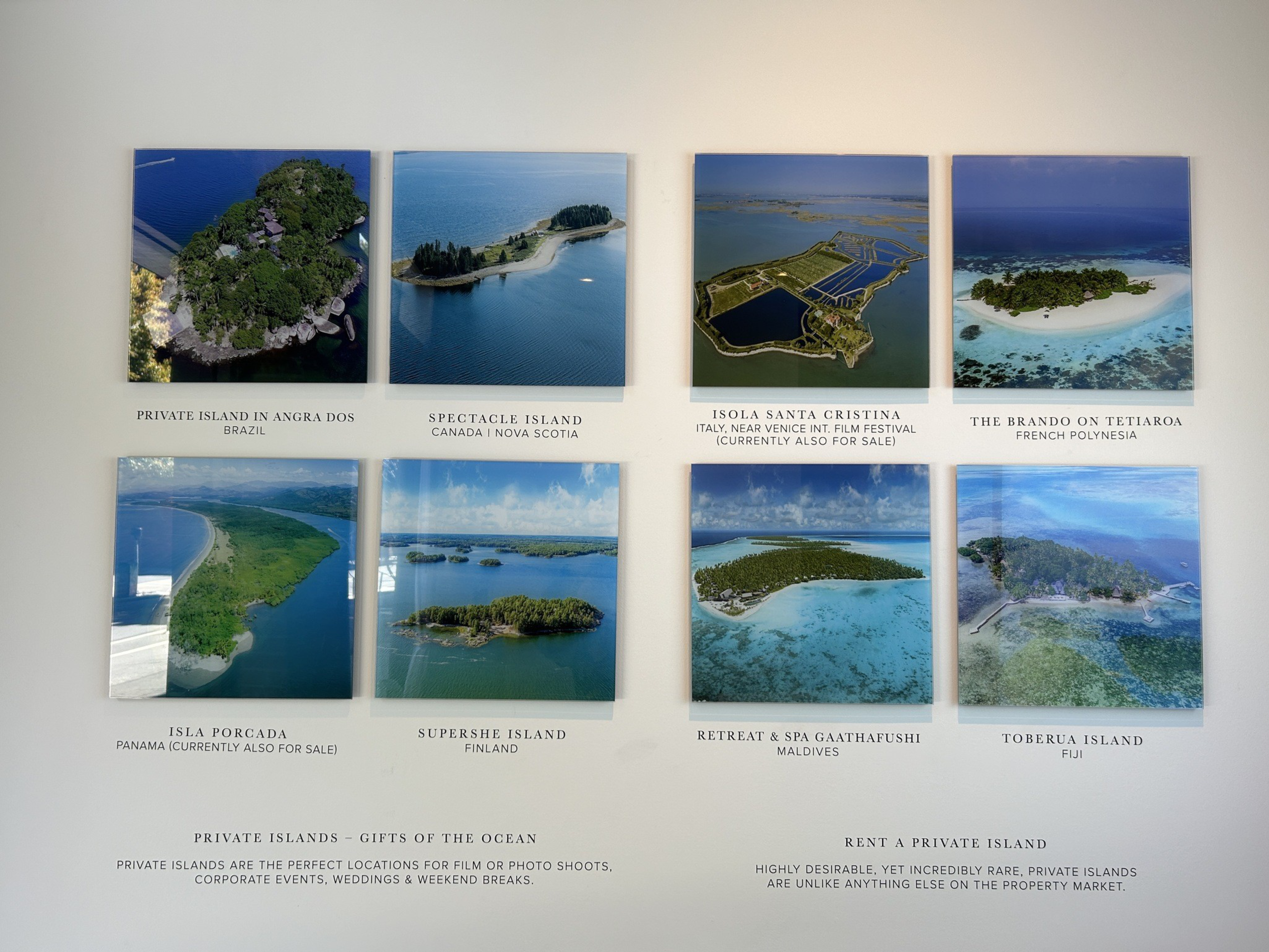 gallery-style, wall-mounted displays of available island properties showing eight tropical locations