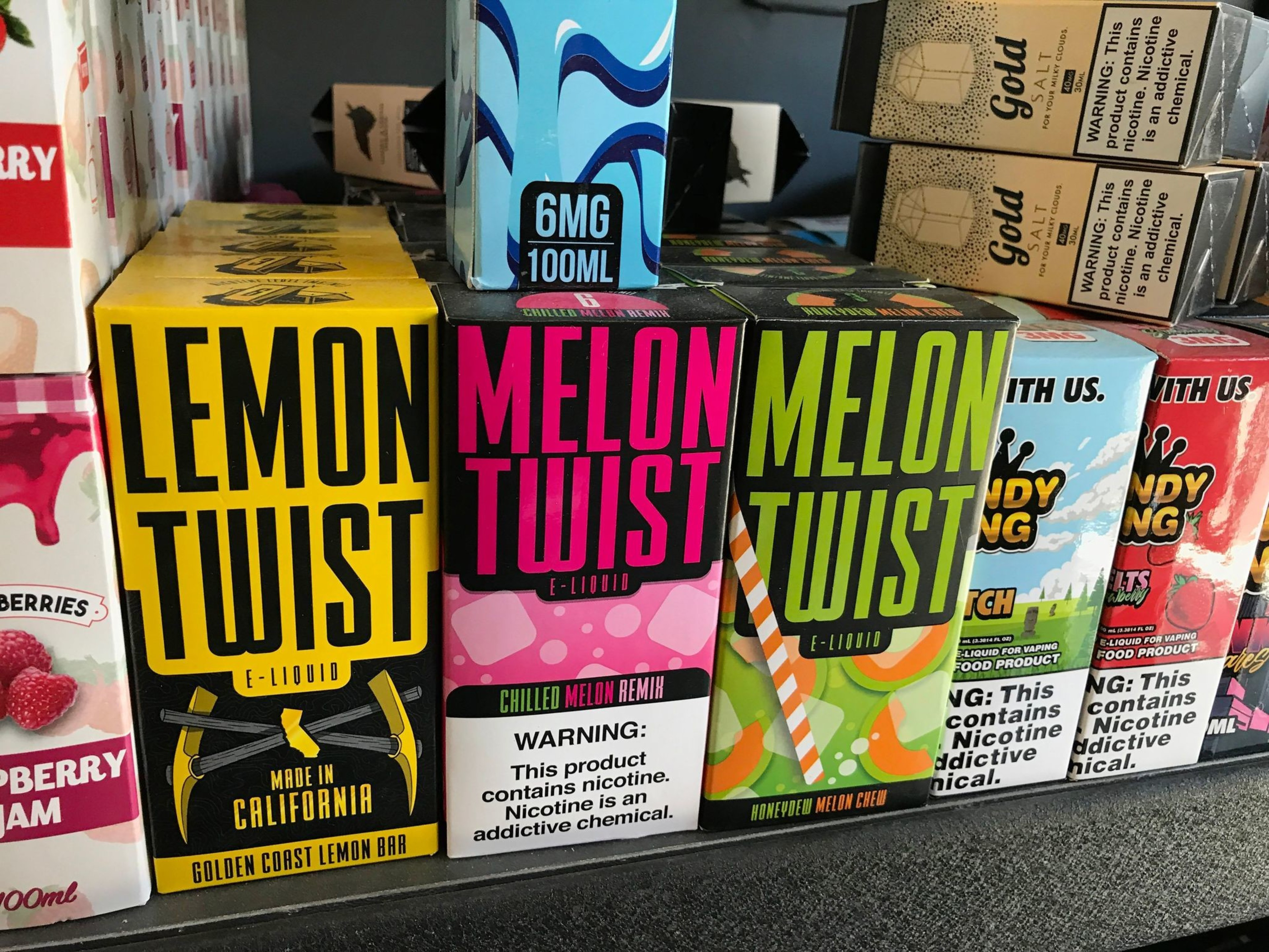 A collection of vape products in various flavors, including lemon twist and lemon twist, on a store shelf.