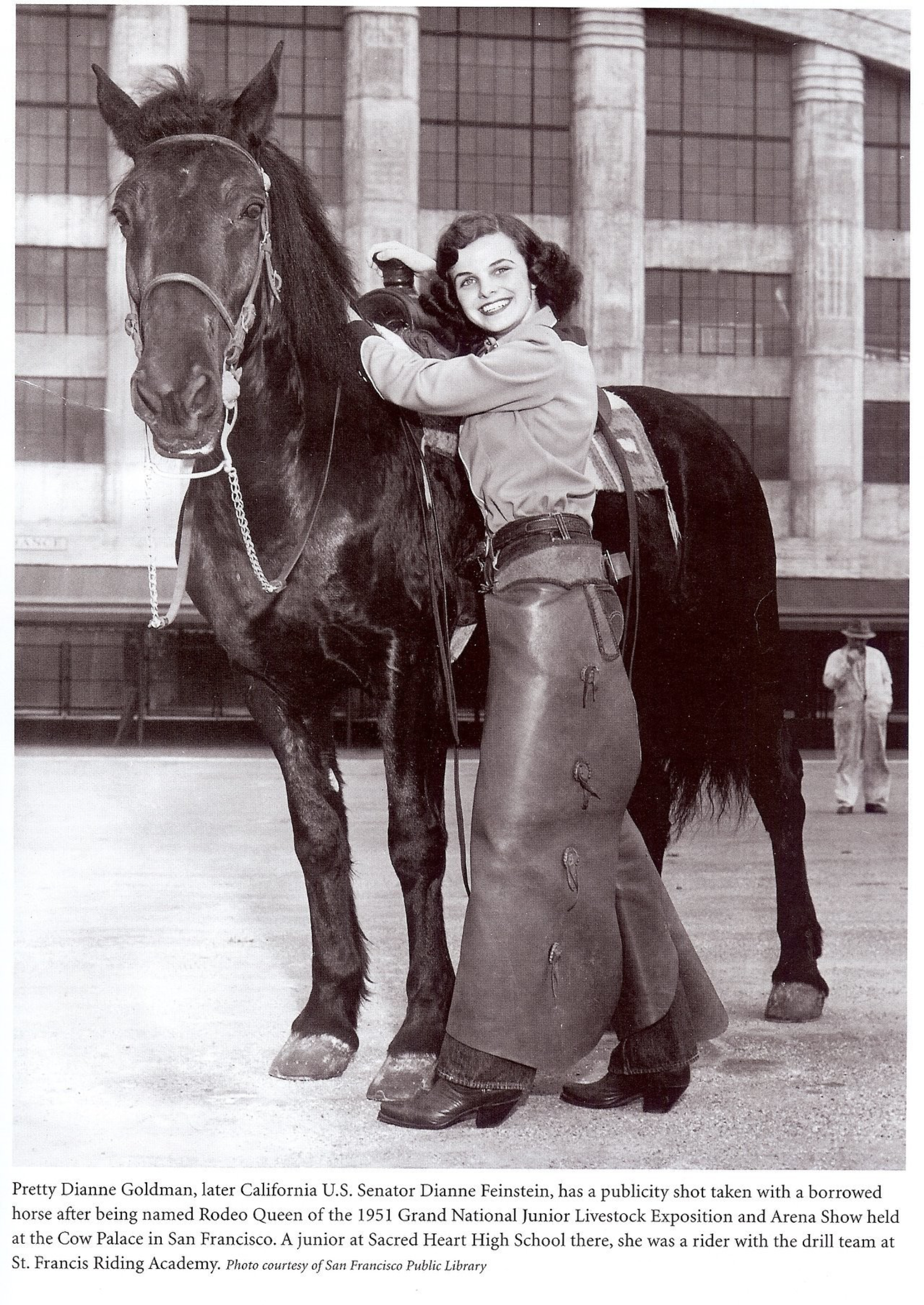 A young Dianne Feinstein embraces a large horse, both posed before the exterior of an arena.
