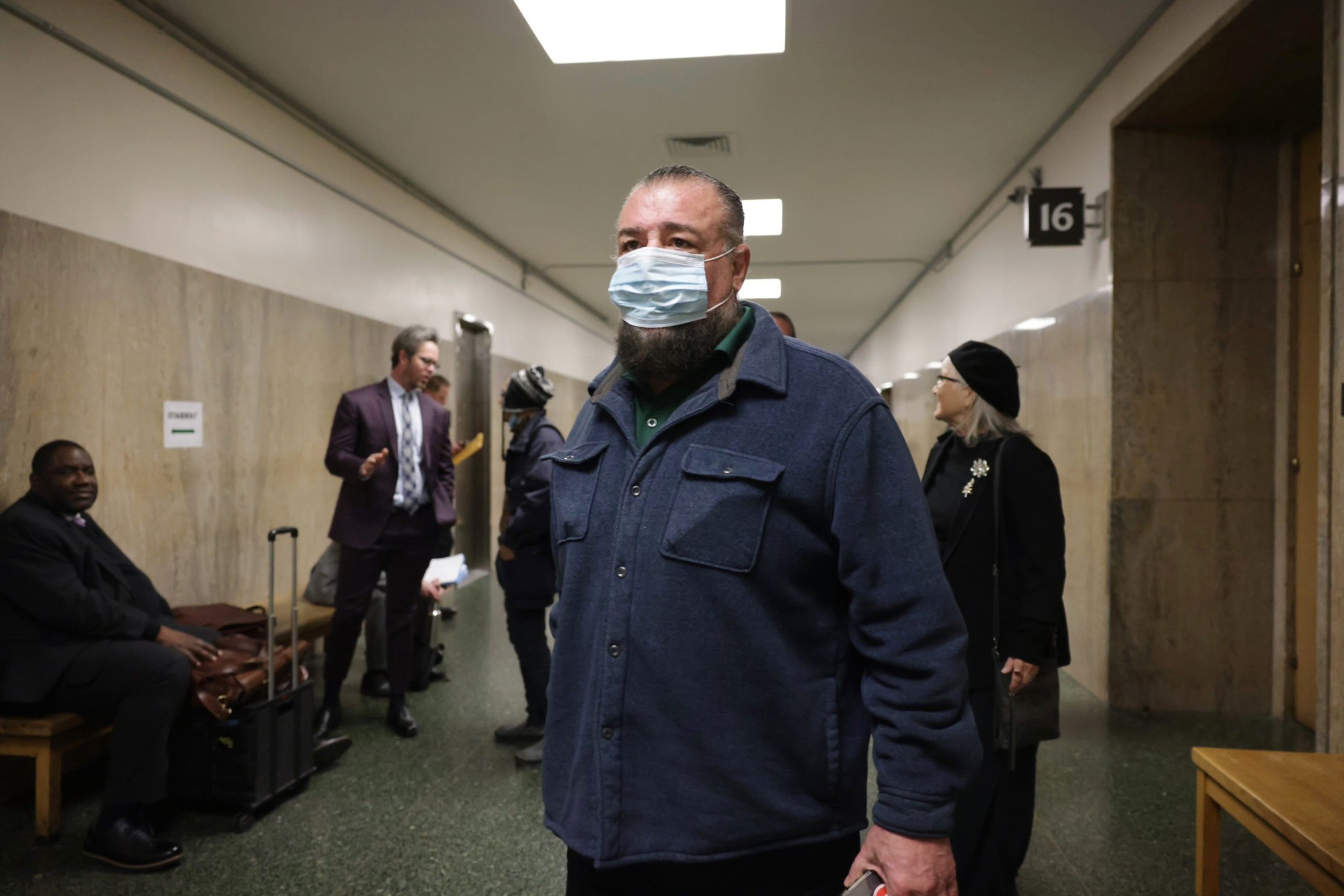 Fomer SFFD Commissioner Don Carmignani, wearing a face mask, walks through the hallways of the Hall of Justice in San Francisco.