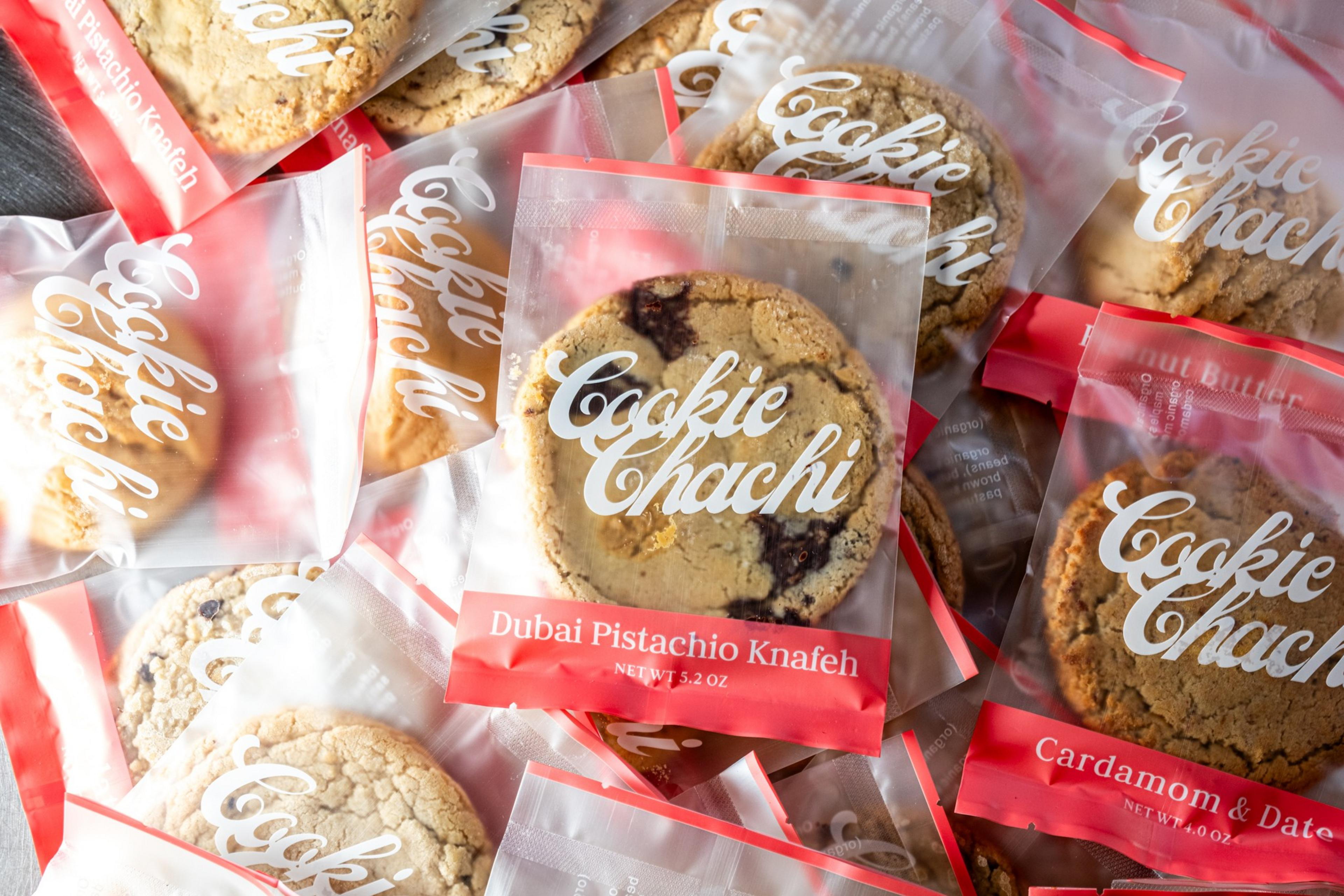 The image shows several packaged cookies labeled &quot;Cookie Chachi,&quot; with flavors like &quot;Dubai Pistachio Knafeh&quot; and &quot;Cardamom &amp; Date&quot; visible.