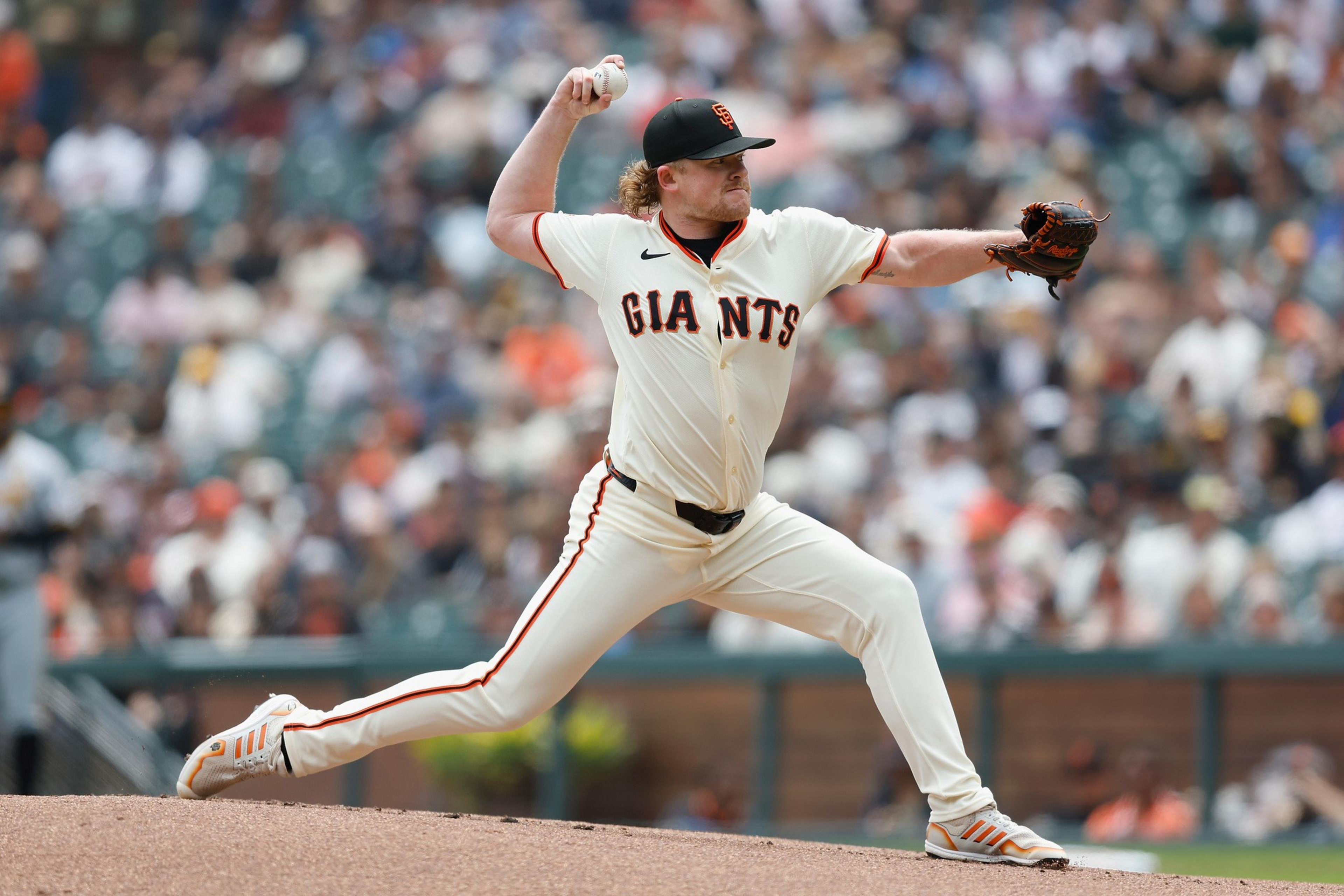 A baseball pitcher for the San Francisco Giants throws a pitch on the mound during a crowded game.