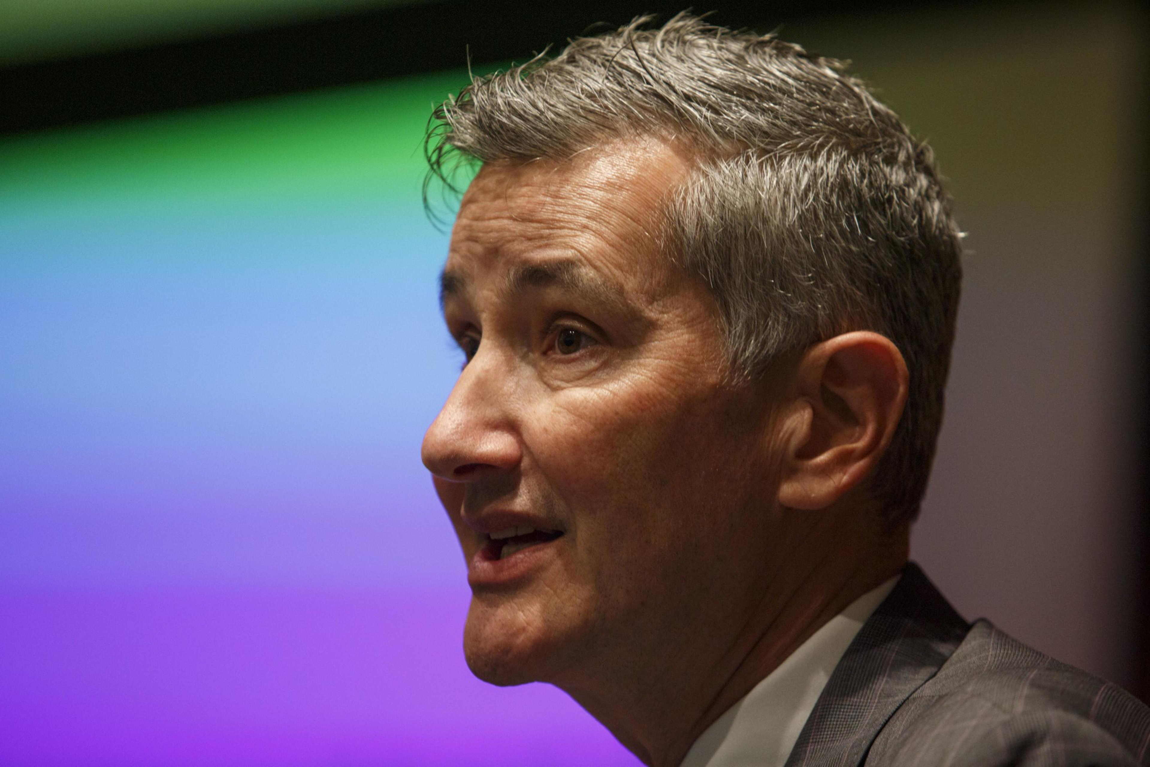 The profile of a man speaking to a crowd. 