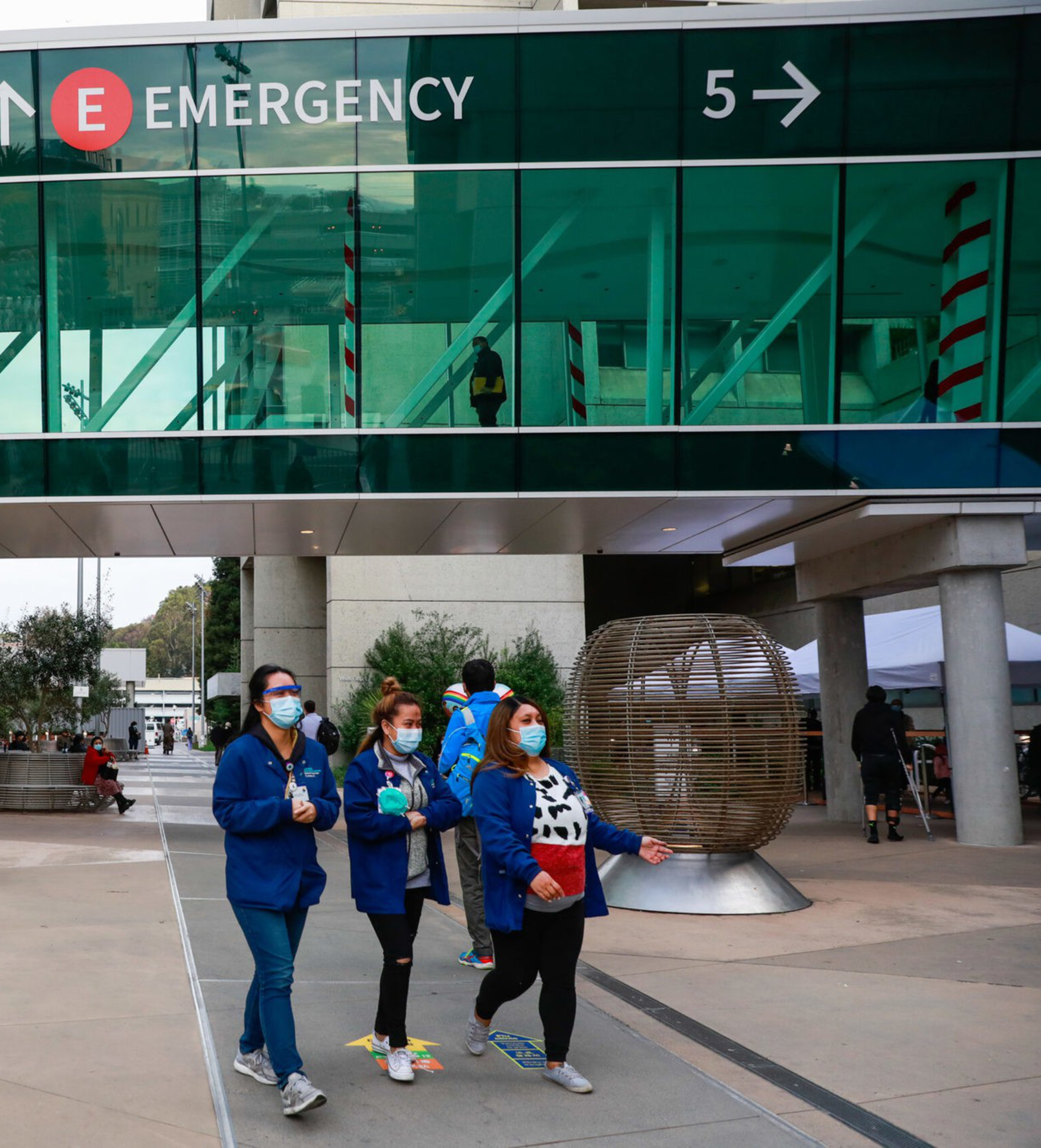people walk outside emergency sign at hospital