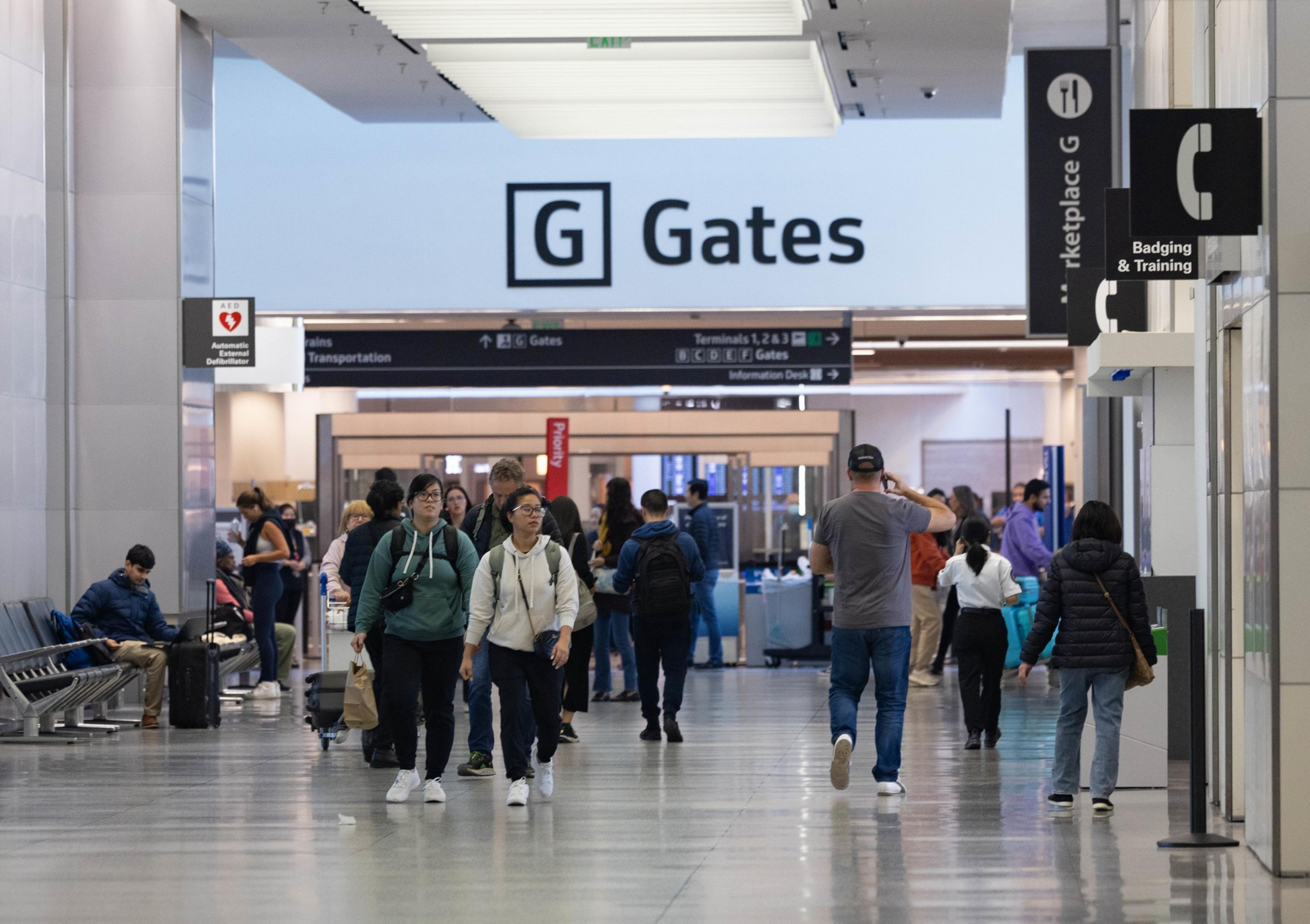 A crowd of people waits at an airport security checkpoint.