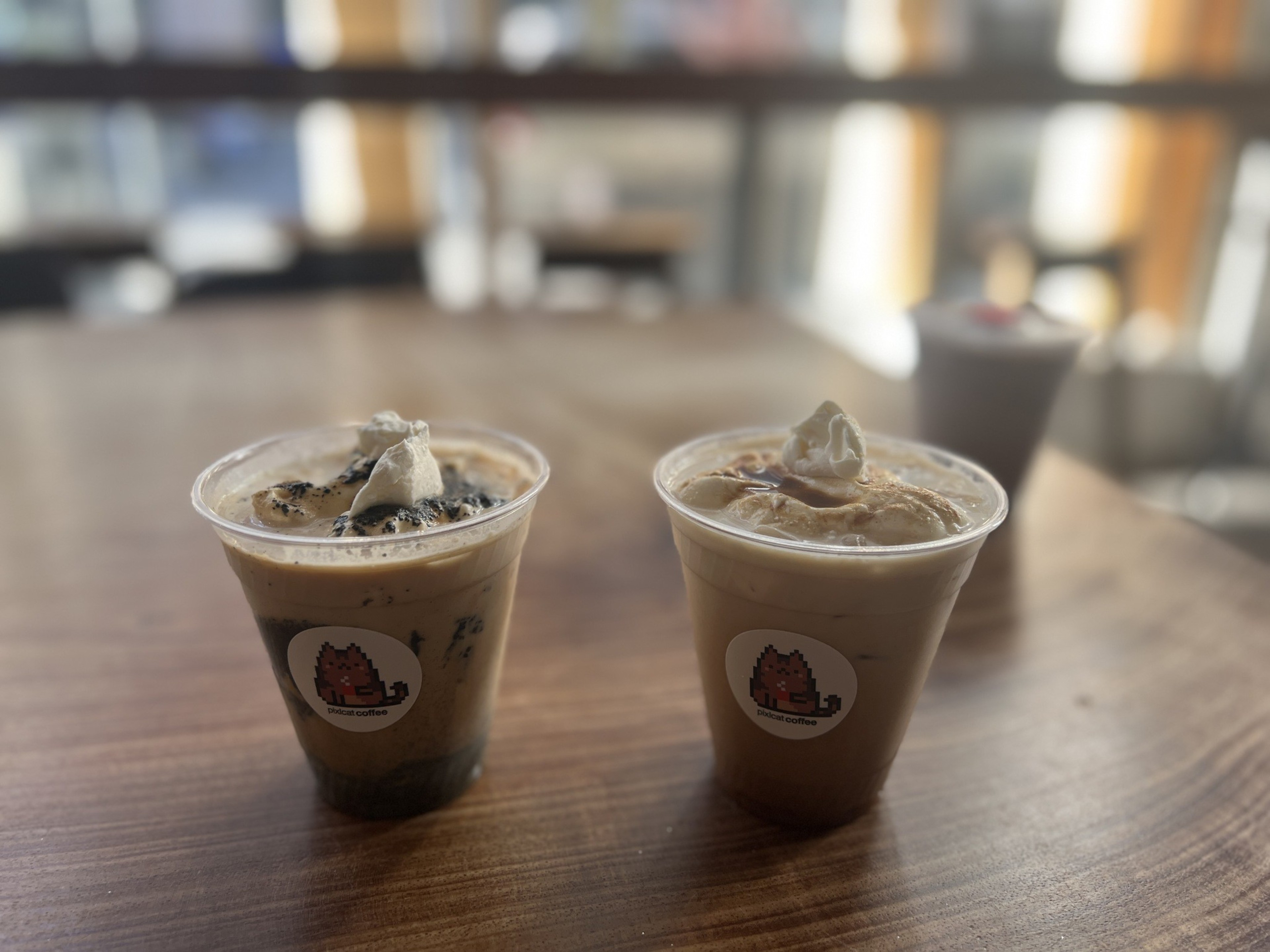 Two iced coffee drinks stand on a wooden table.