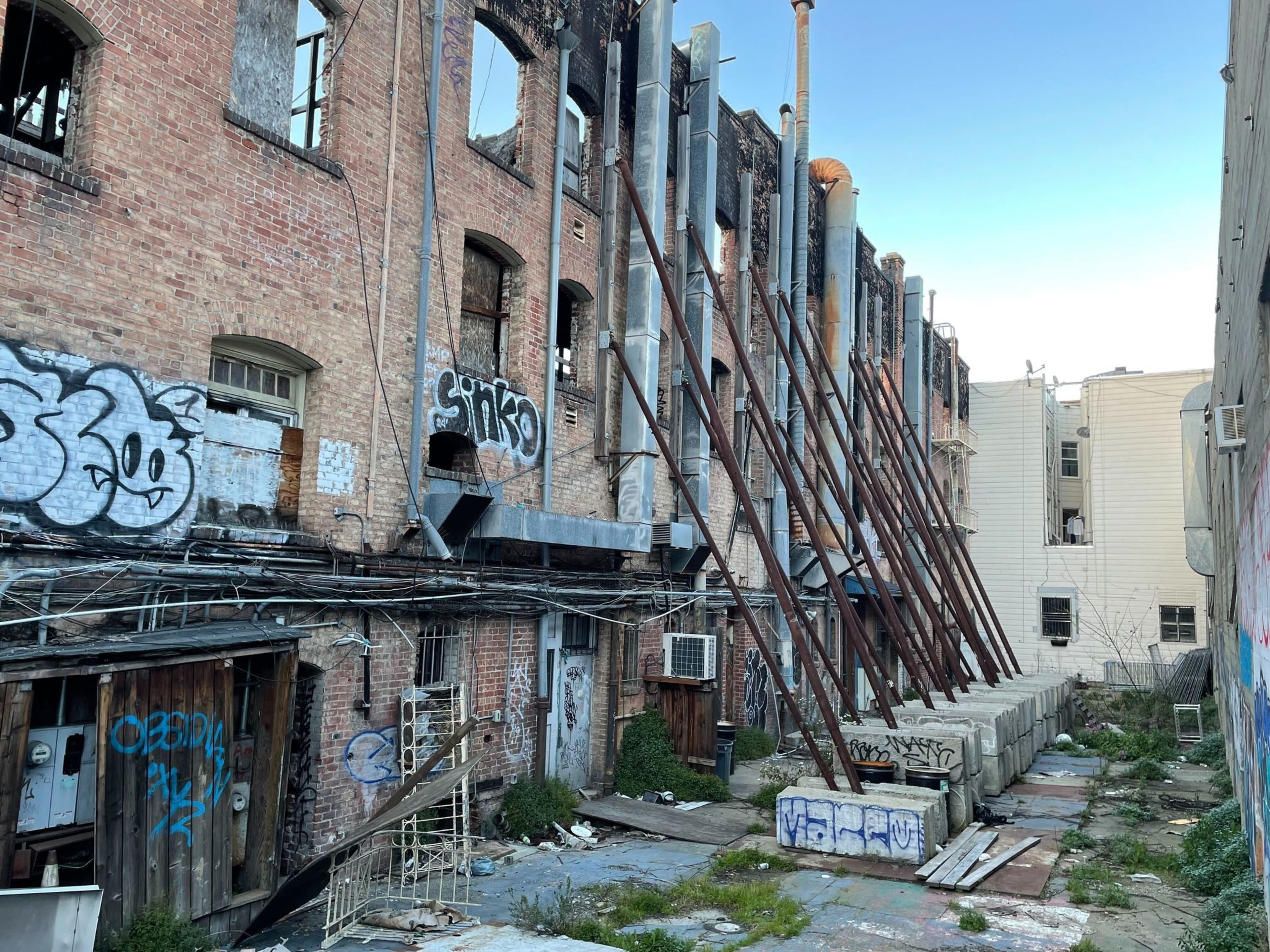 Metal poles prop up a brick wall.