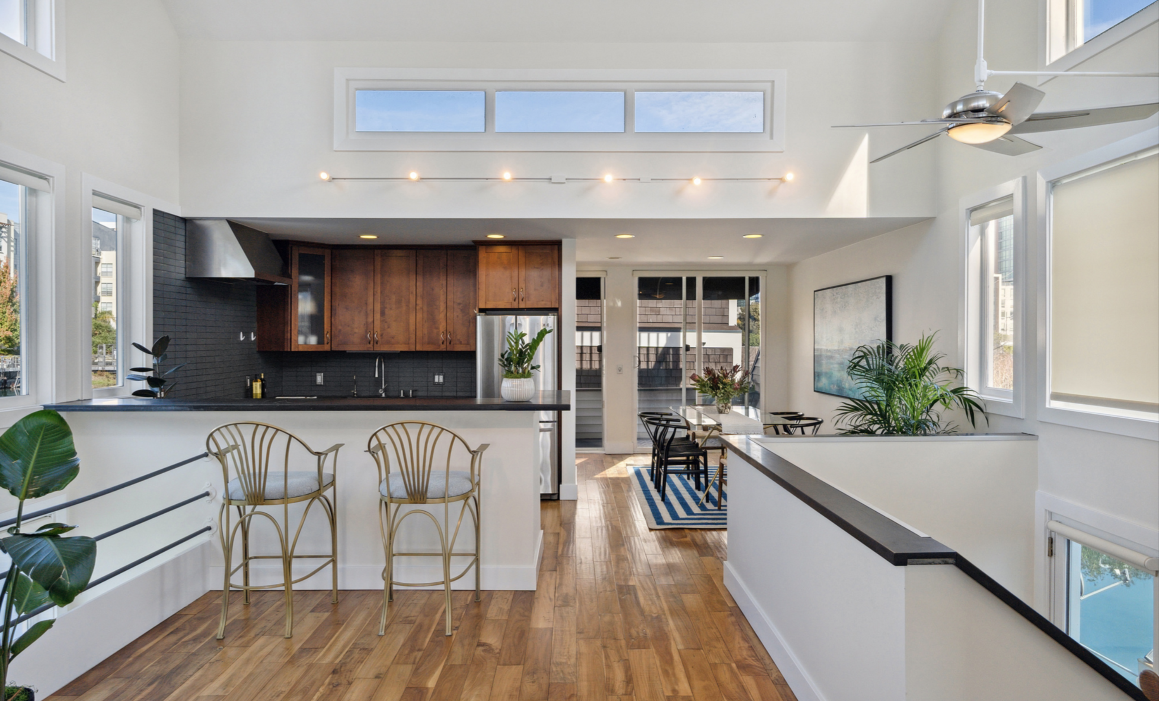 The houseboat's kitchen features white walls, gray tiles and slender golden chairs.