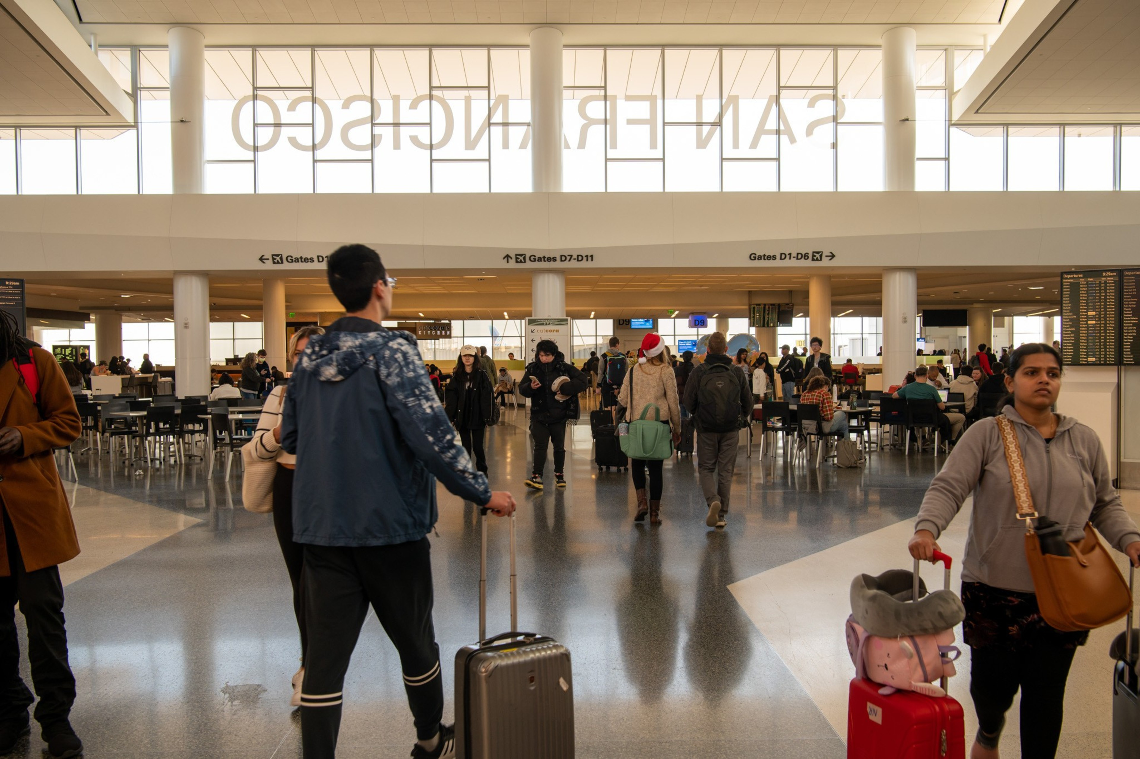 Travels in SFO terminal walking with their luggages.