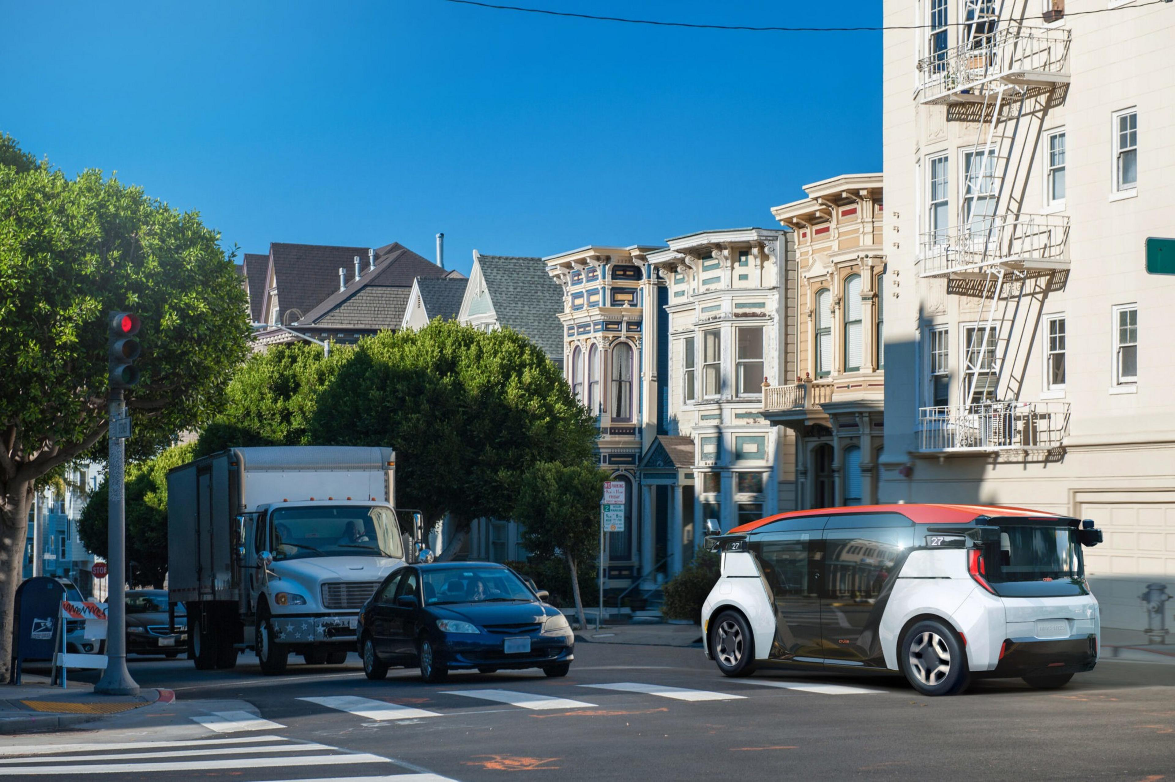 A futuristic white and orange autonomous vehicle waits at a crosswalk near a truck and car, with Victorian-style buildings and trees in the background.