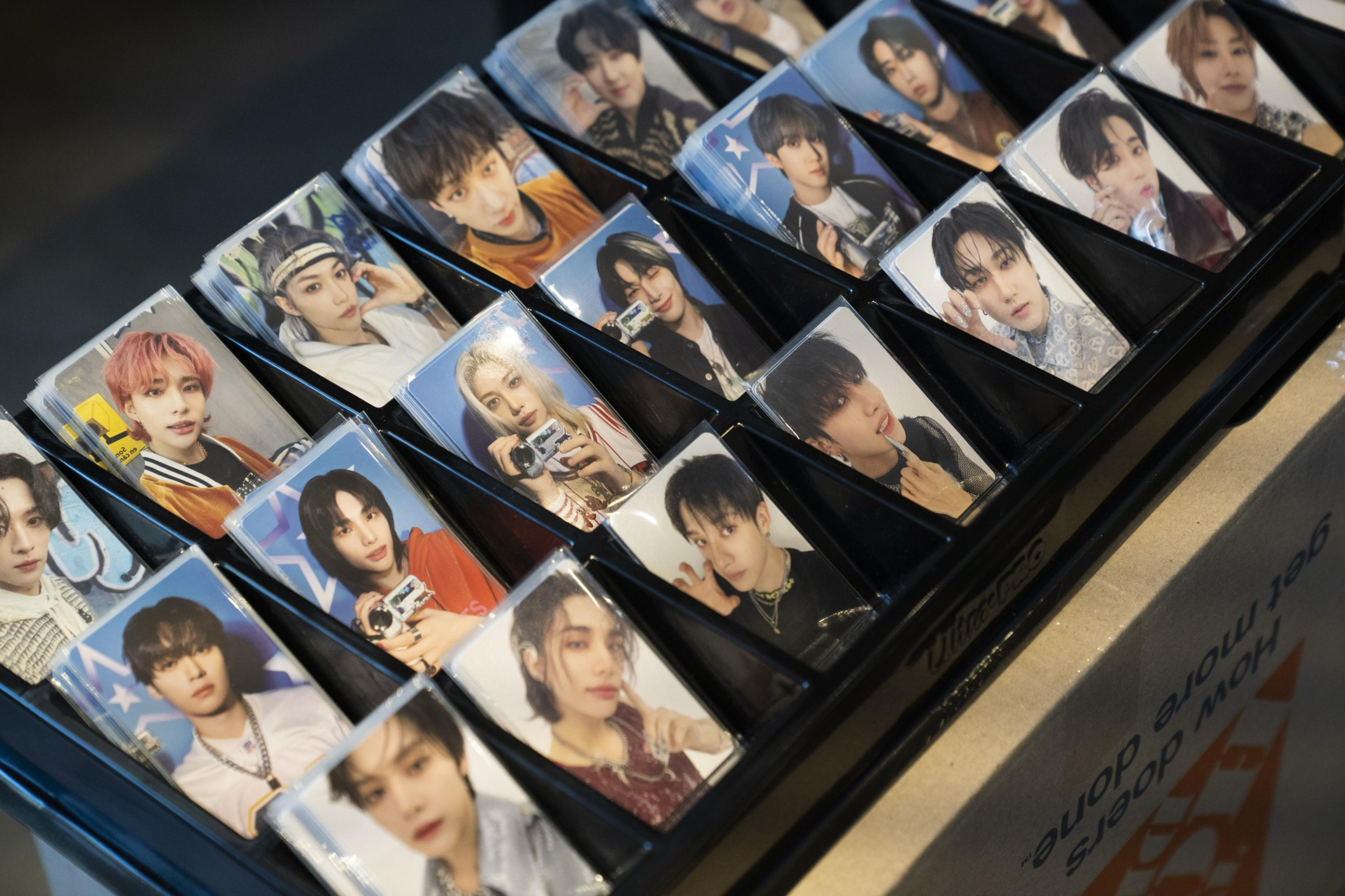 The image shows a display of collectible photo cards featuring various individuals, each posing uniquely. The cards are neatly arranged in rows on a tray.