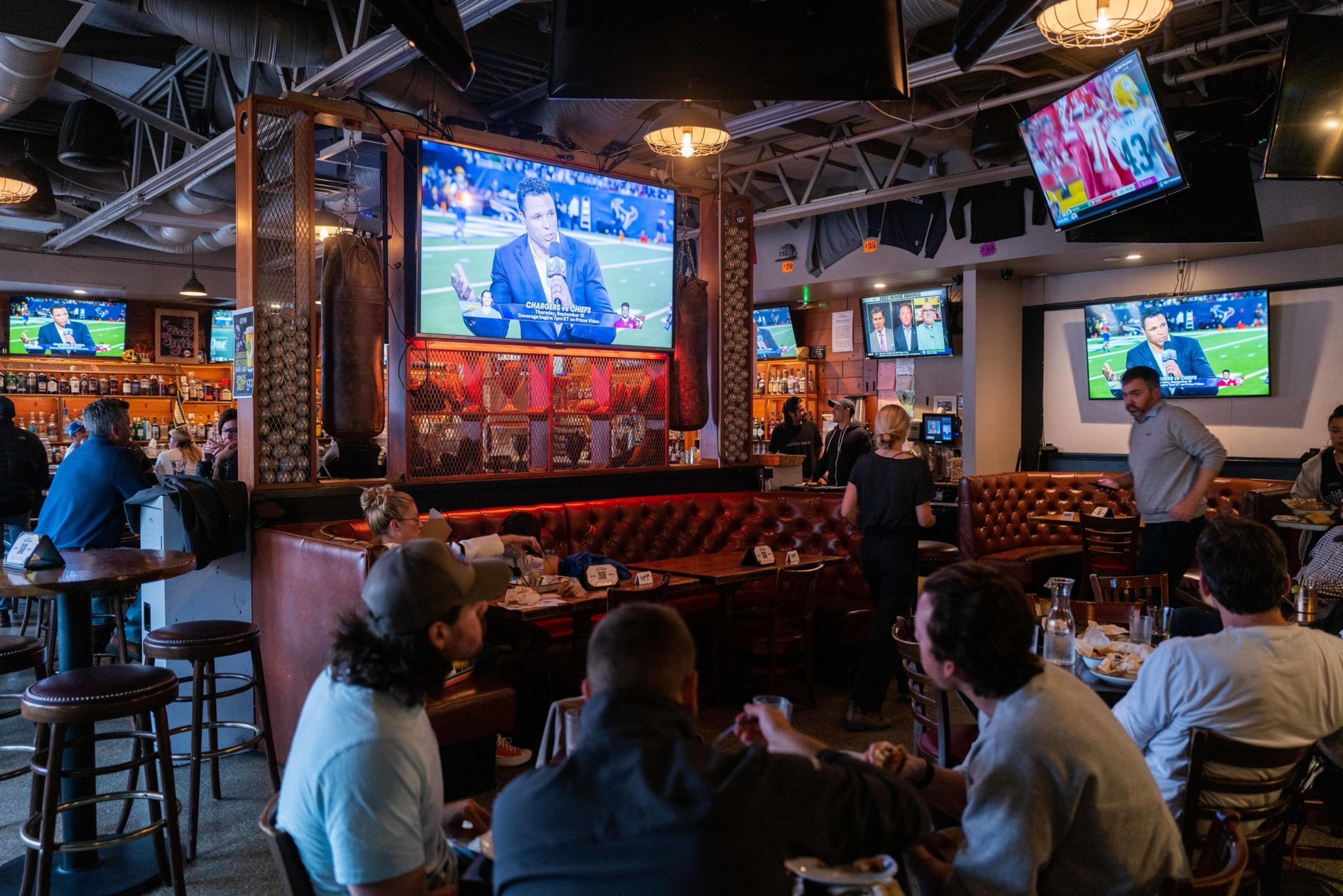 A sports bar has people crowded around watching a television.