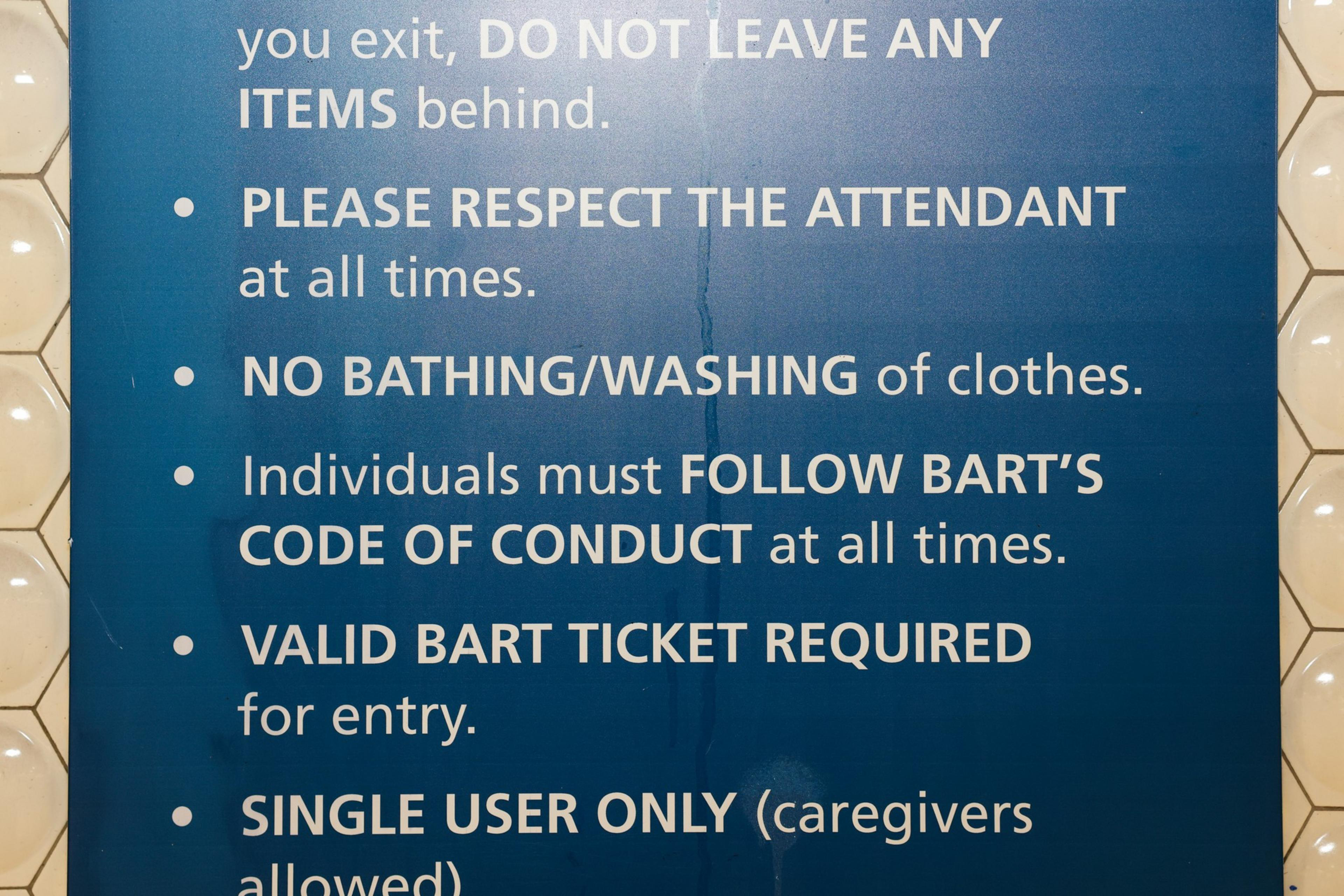 The image shows a blue sign listing BART rules: respect attendants, no bathing, follow conduct codes, require valid tickets, and single user entry.
