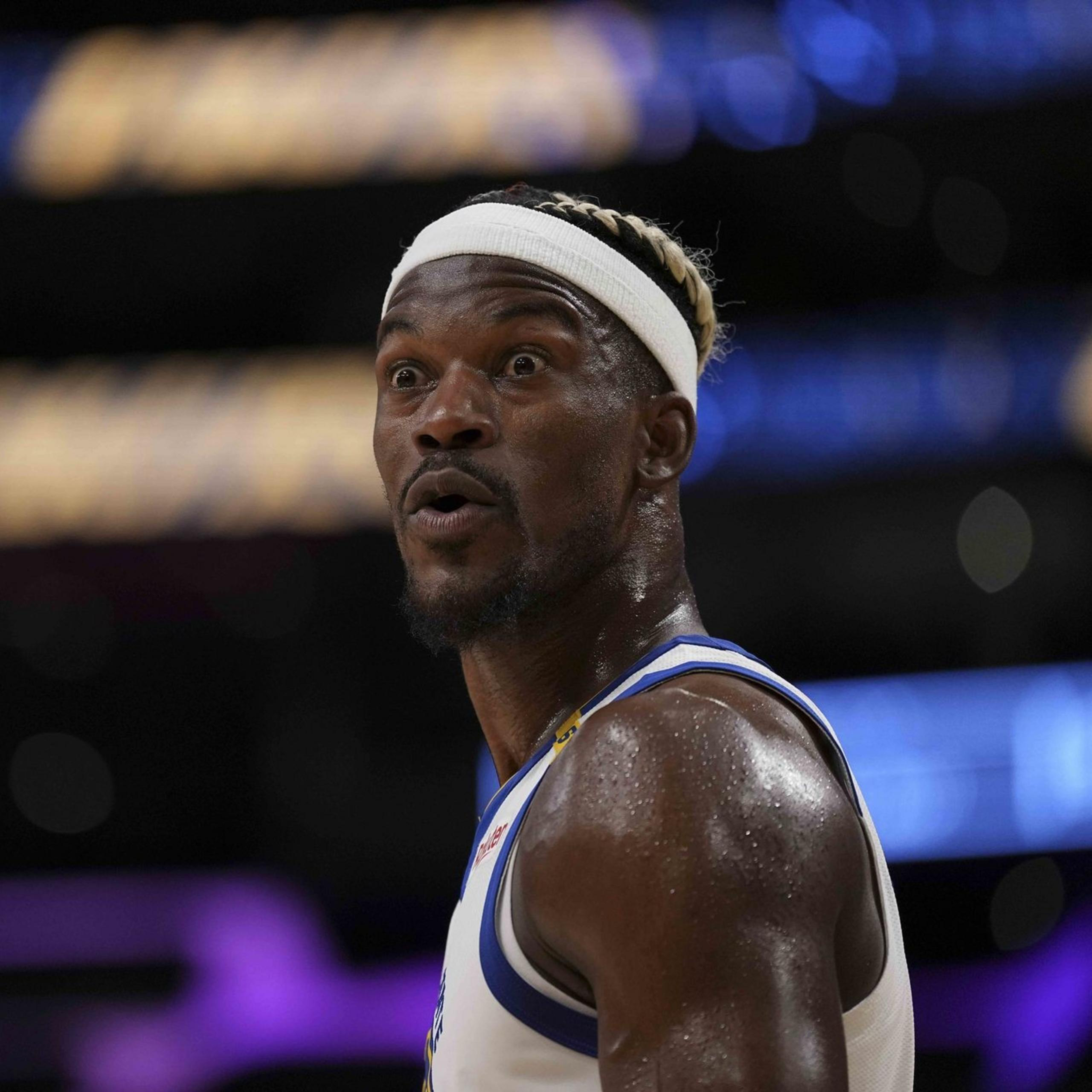 A basketball player with a white headband and jersey looks surprised. The background is blurred with purple and blue tones, focusing attention on his expression.
