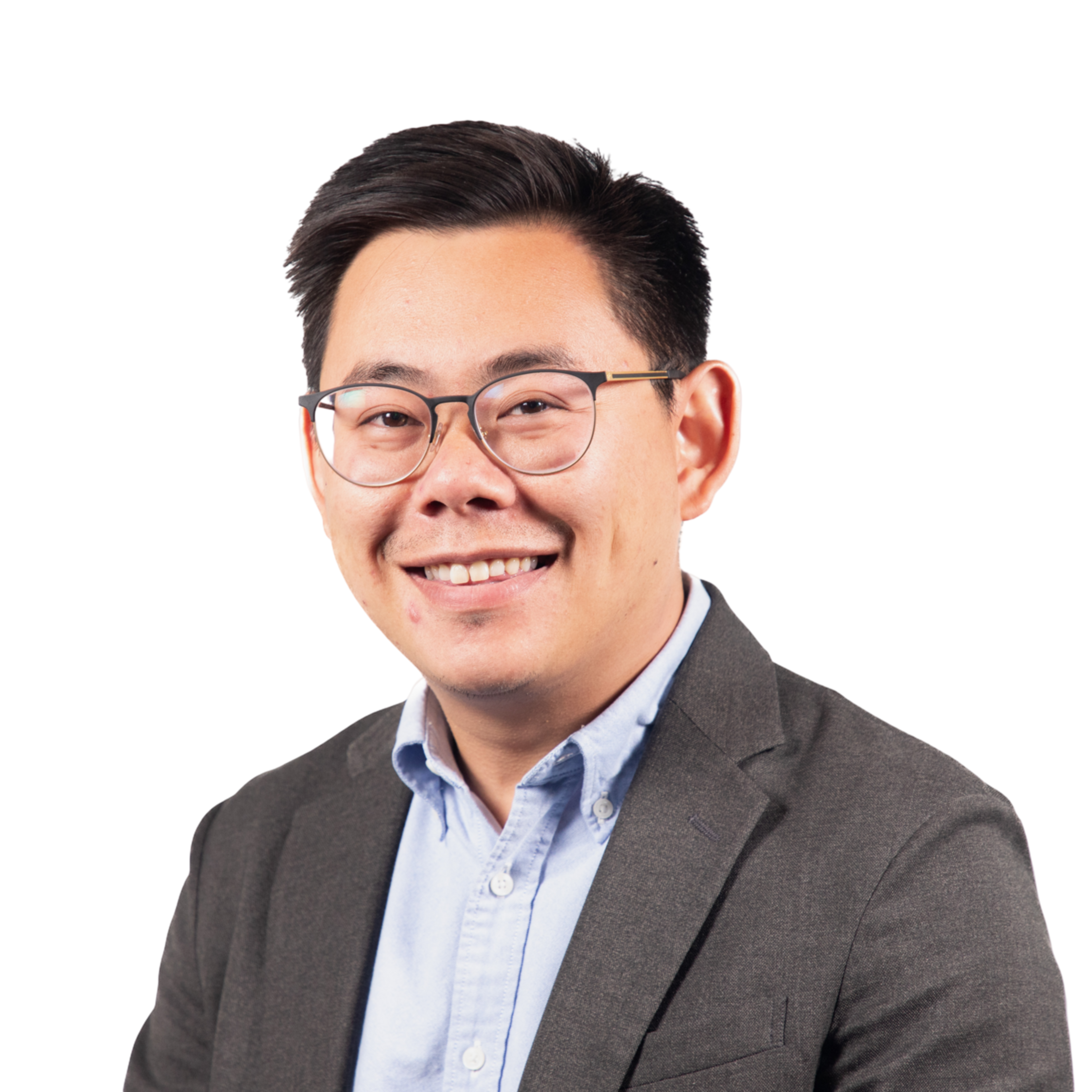 A smiling man with short black hair and glasses wears a light blue button-up shirt under a dark gray blazer.