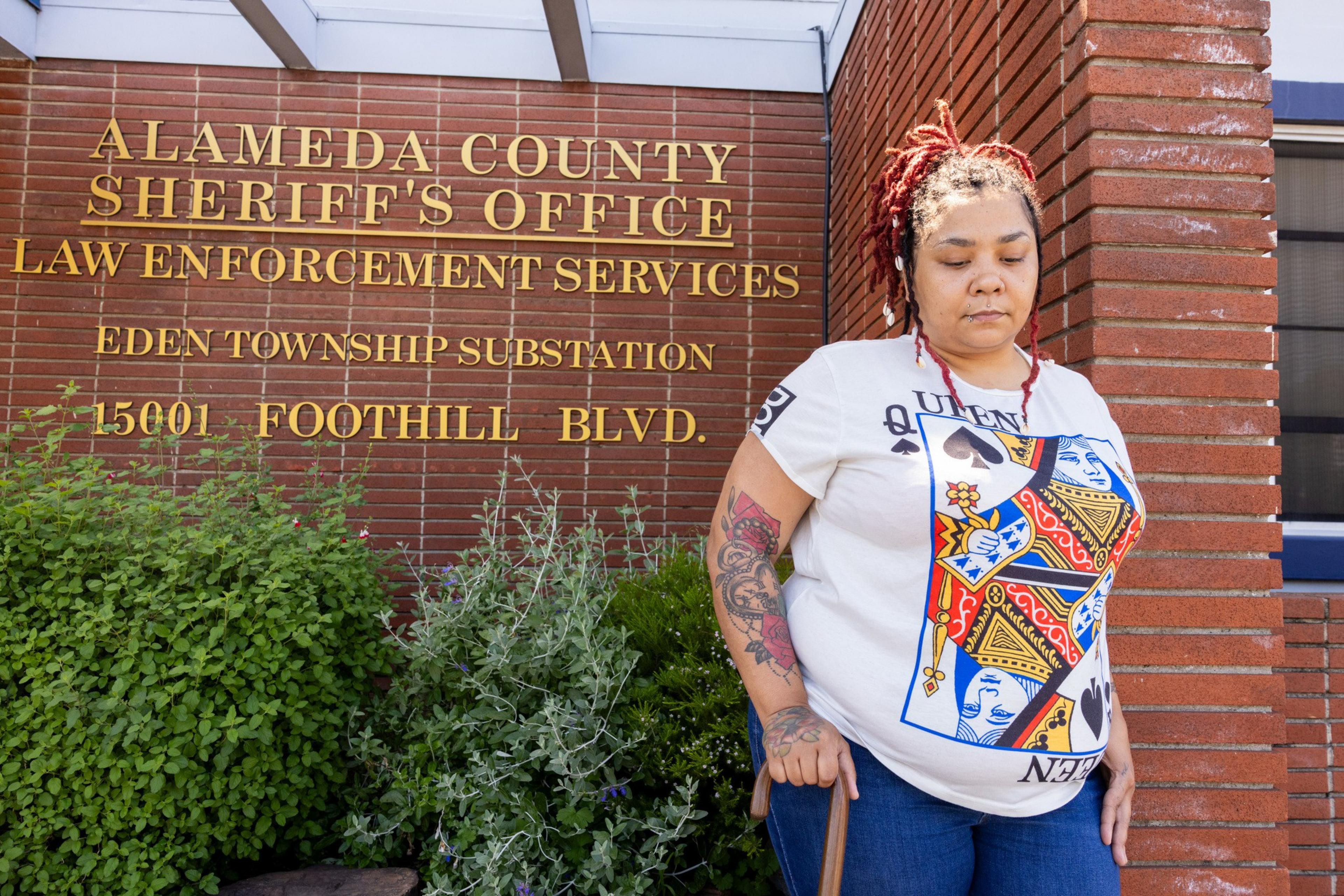 A person stands by a brick wall with signage for Alameda County Sheriff's Office.