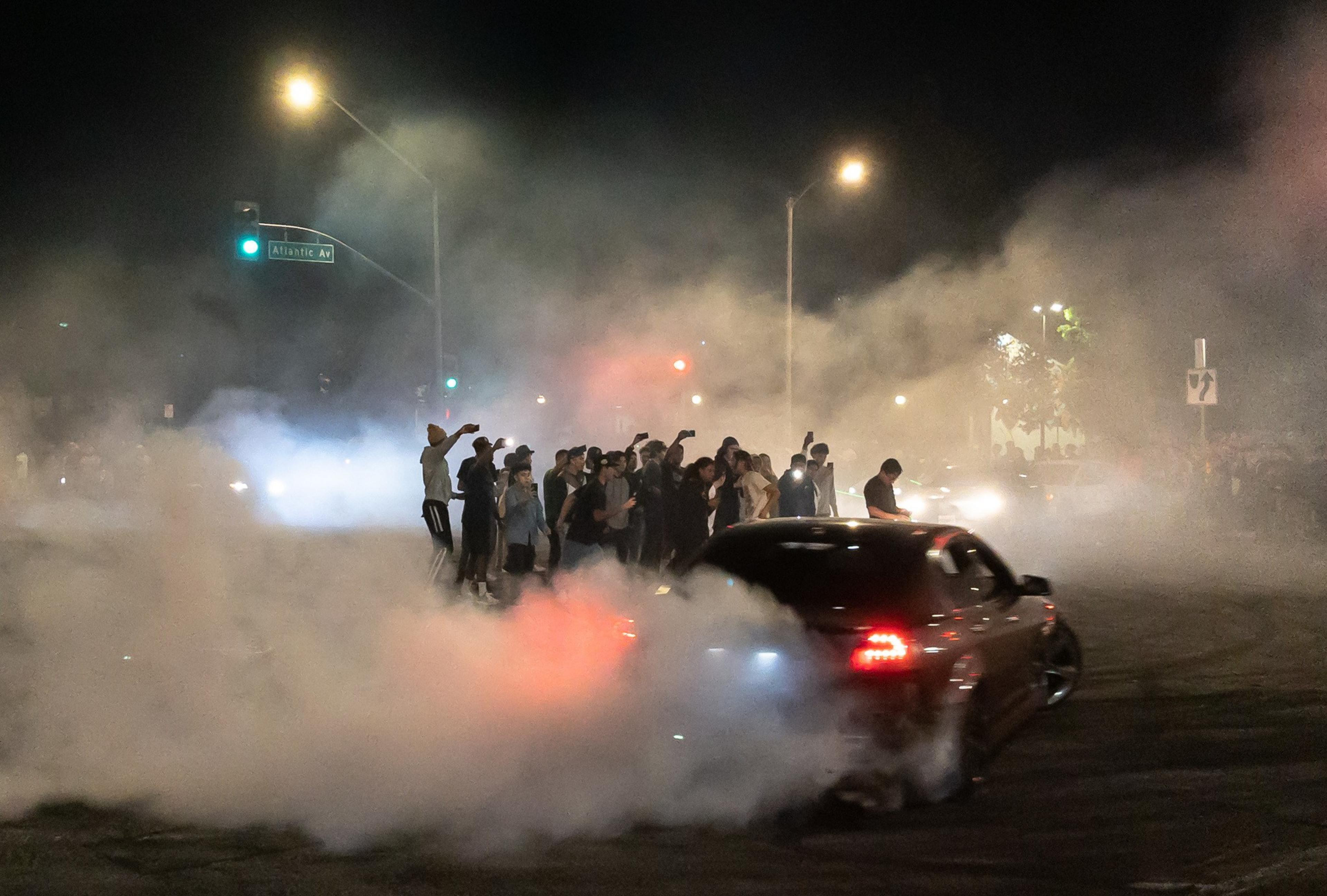 A car drifts around spectators gathered in the middle of the intersection during an early morning street sideshow at Compton Boulevard and Atlantic Avenue in East Compton on Sunday, Aug. 14, 2022. Takeovers are a growing trend and residents say that law enforcement are not doing enough to stop them. There have been some residents who say that the events are dangerous and keep them up at night. Some spectators said they feel like they're not bothering anyone and they only happen at night when the streets are empty.