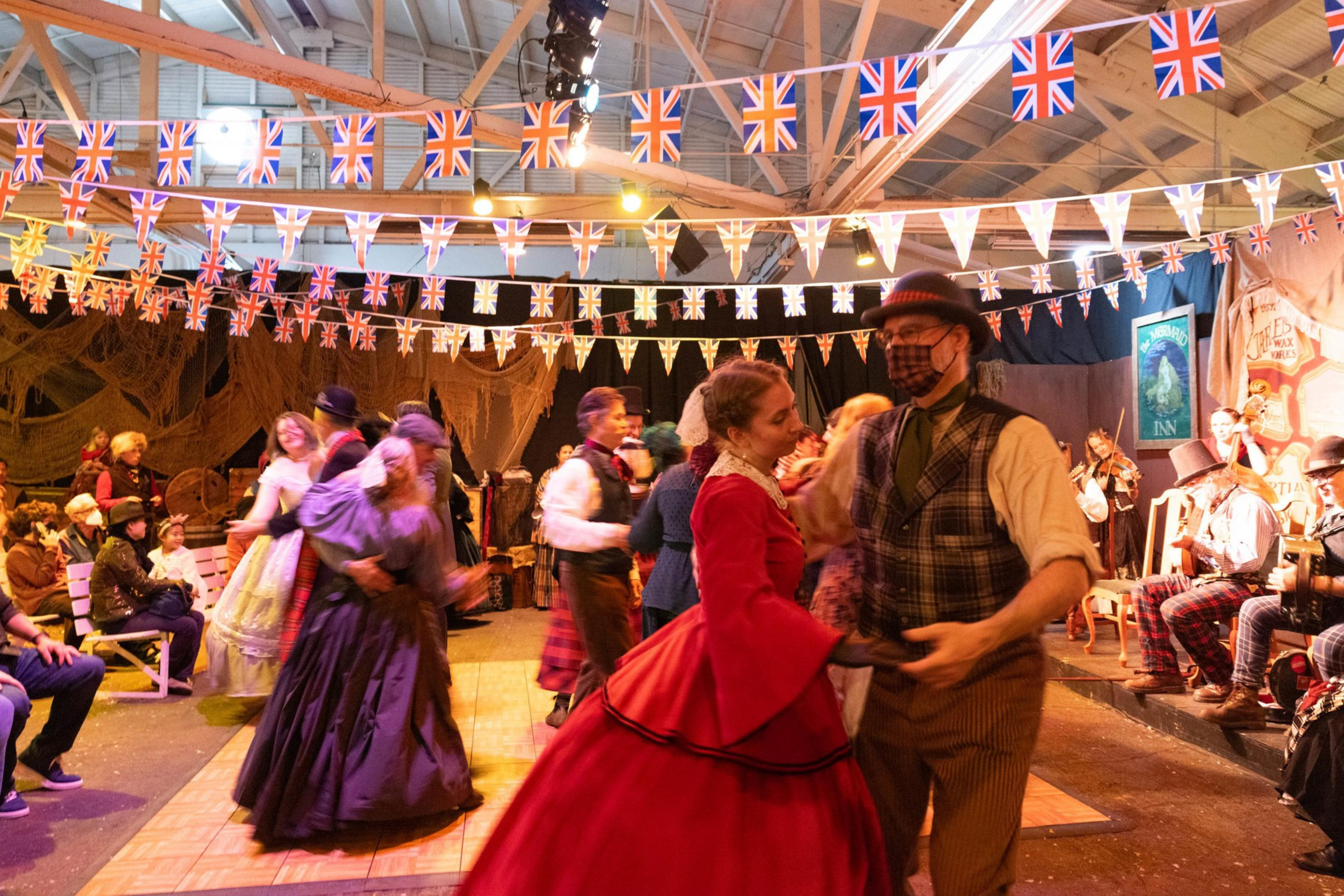 Couples dance while clad in Victorian era clothing at the Great Dickens Christmas Fair.
