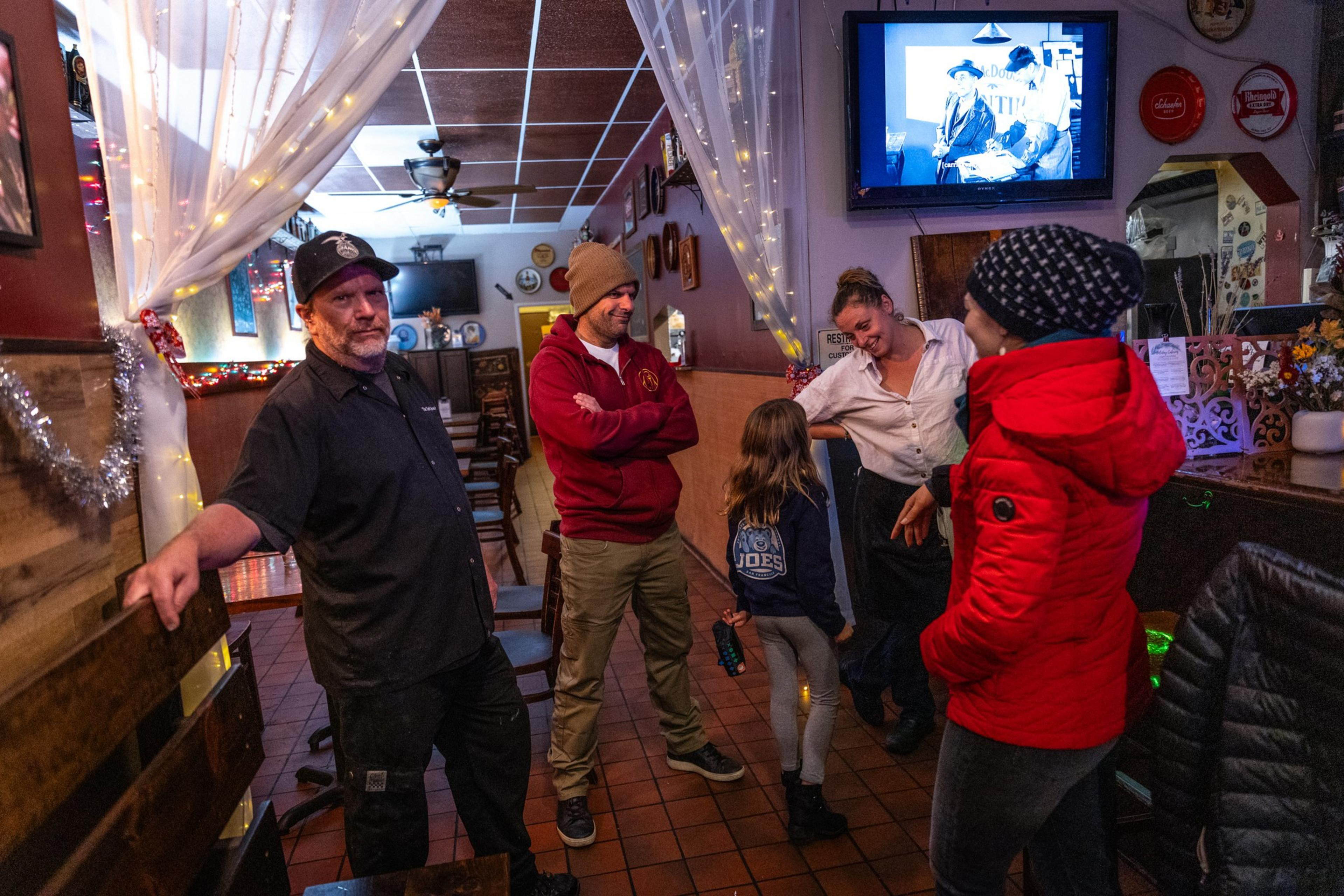 A group of people stand around talking to one another in a bar restaurant setting.