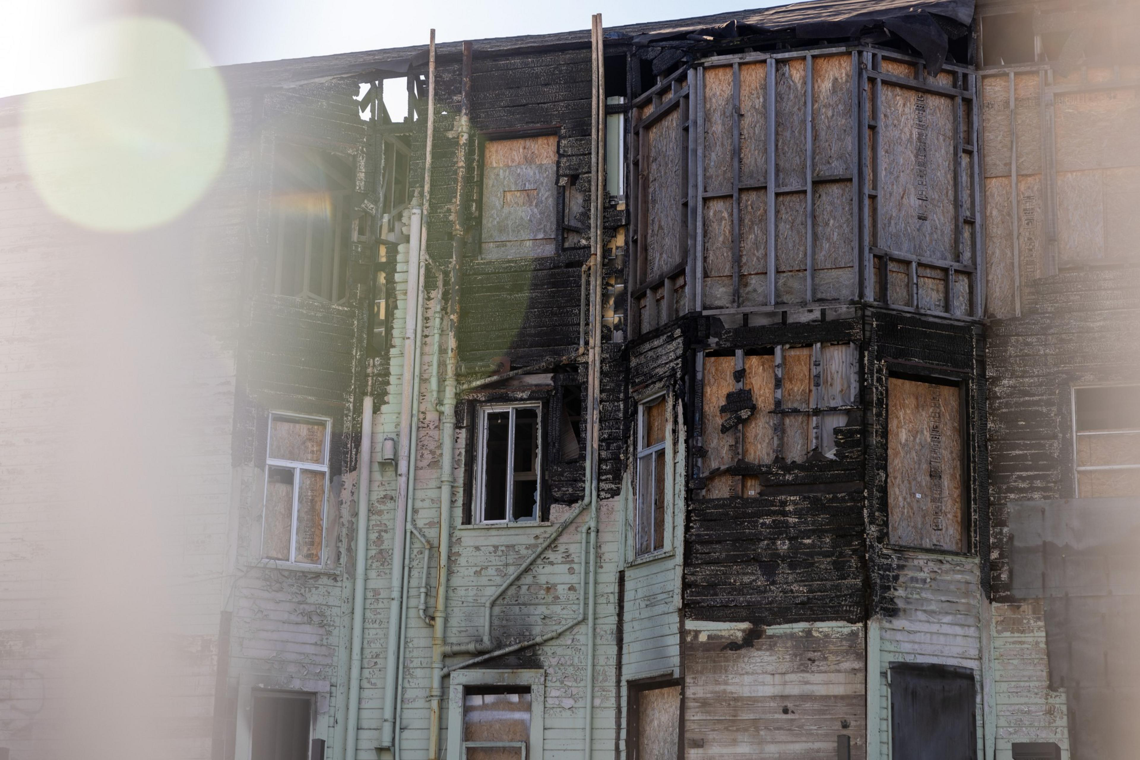 A burned-out building with charred walls, missing windows, and exposed wooden beams.