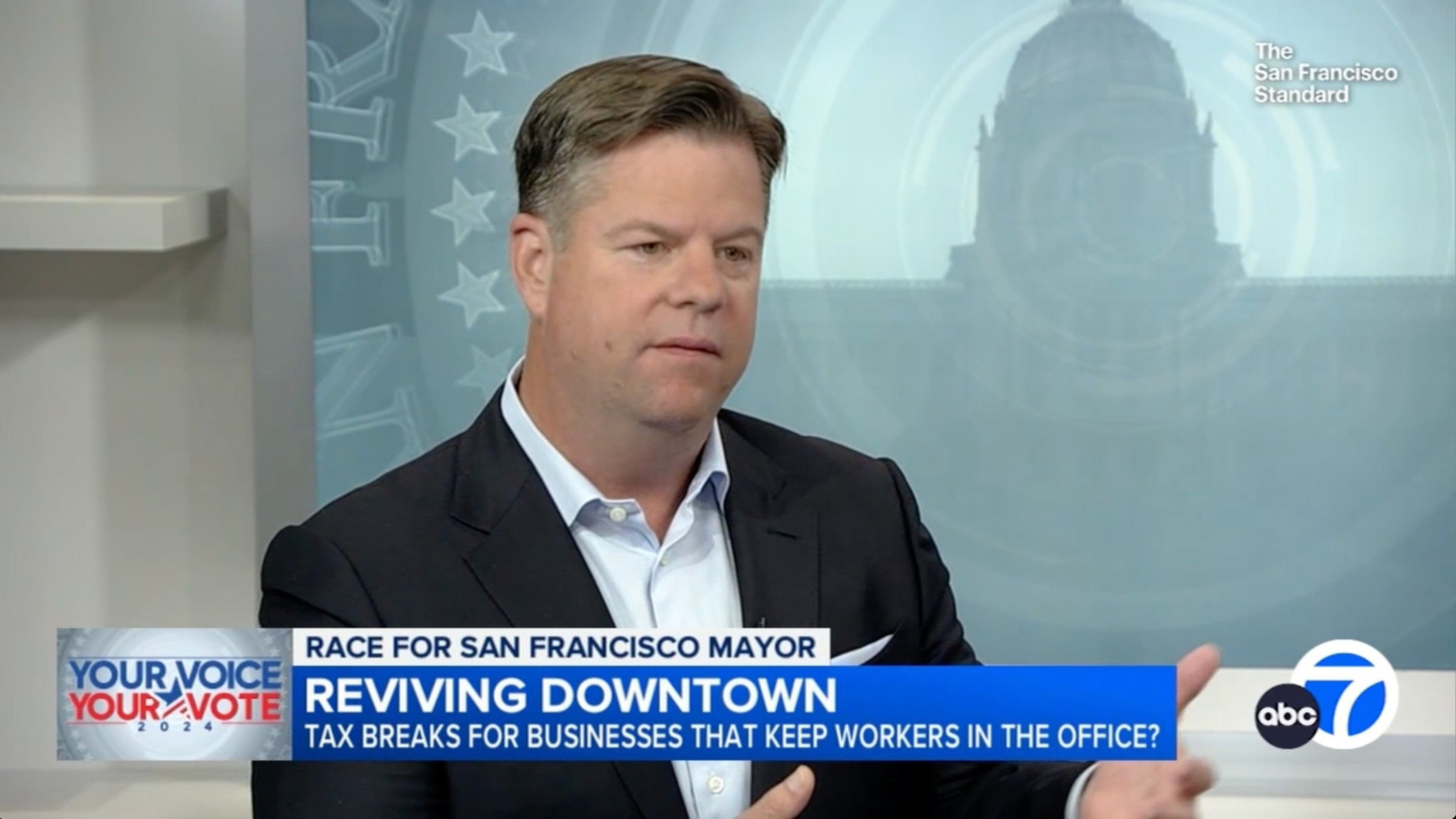 A man in a suit is being interviewed on TV about San Francisco's mayoral race. The banner reads, &quot;Reviving Downtown: Tax breaks for businesses?&quot;