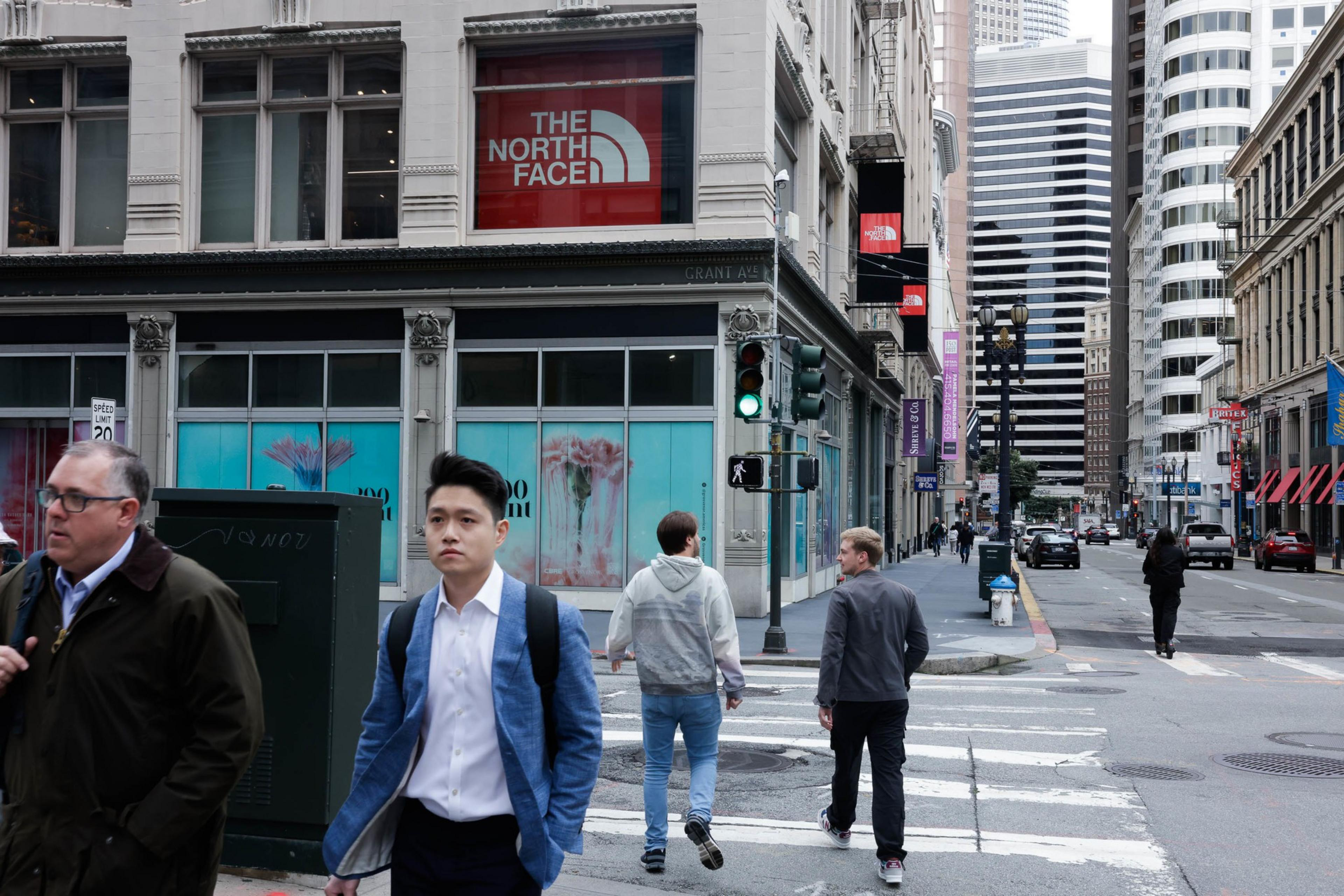 A busy urban street with pedestrians, storefronts, and city architecture.