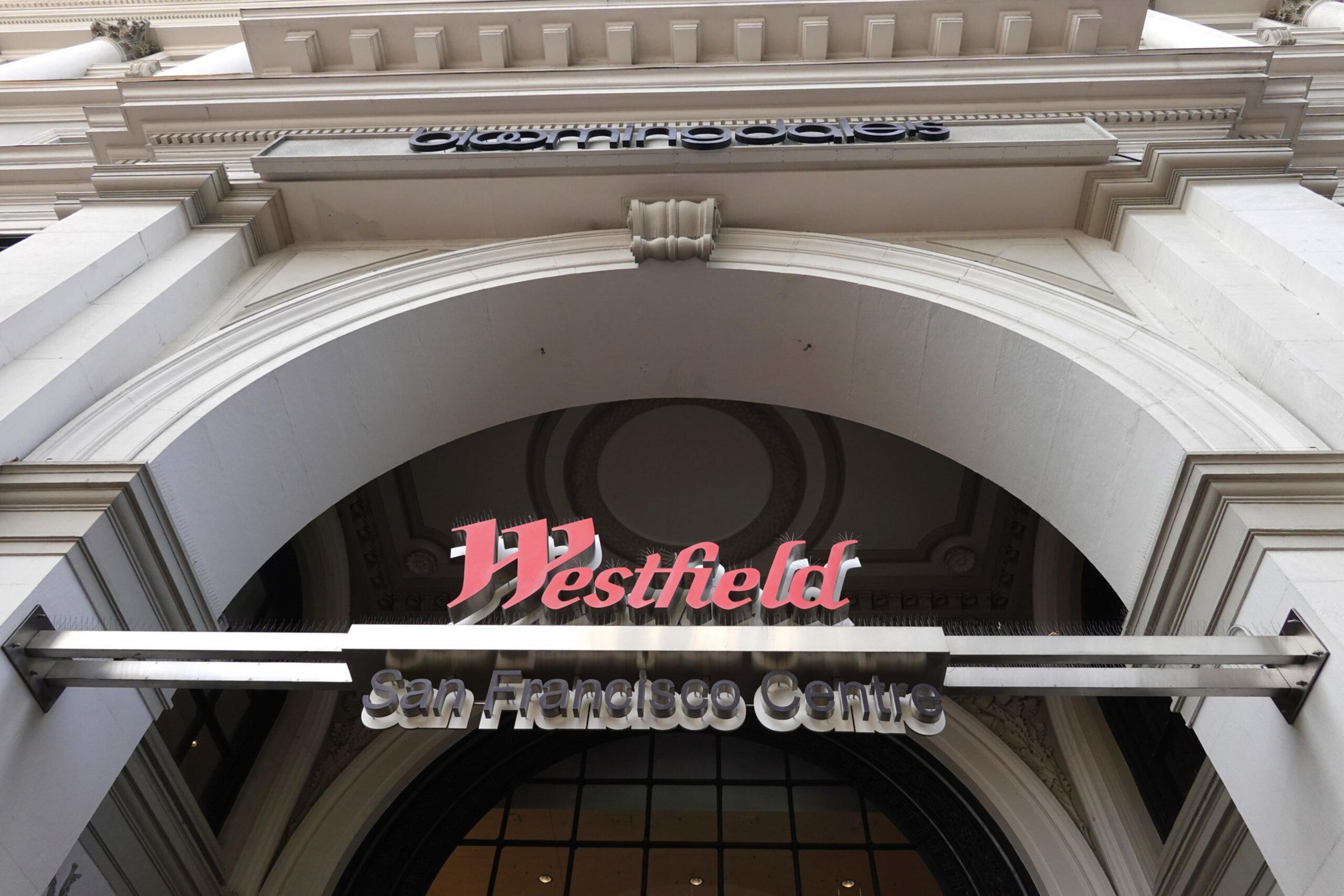 A large white stone archway with a sign reading "Westfield San Francisco Centre" hanging in the center below ornate architectural details.