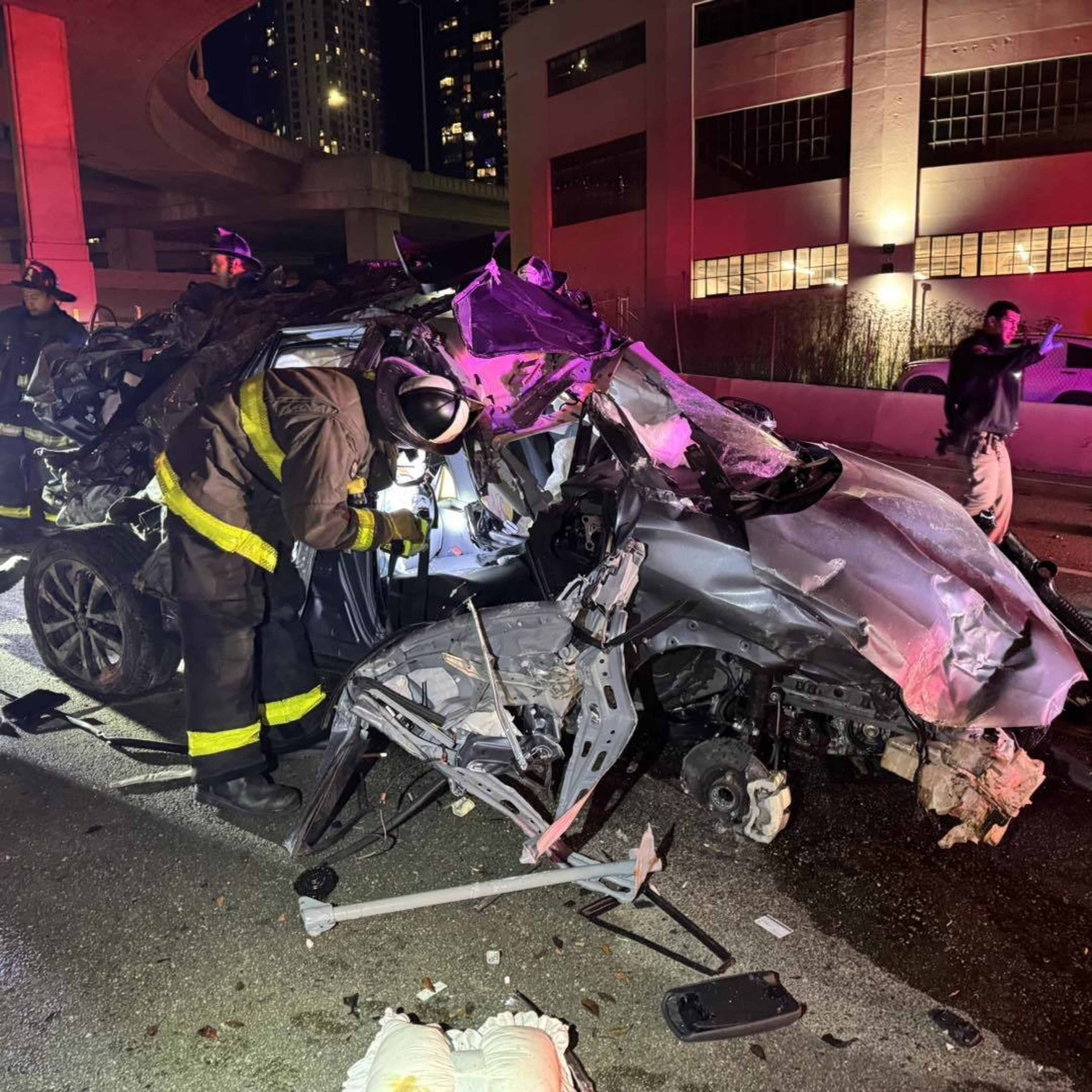 A firefighter peers into a smashed car.