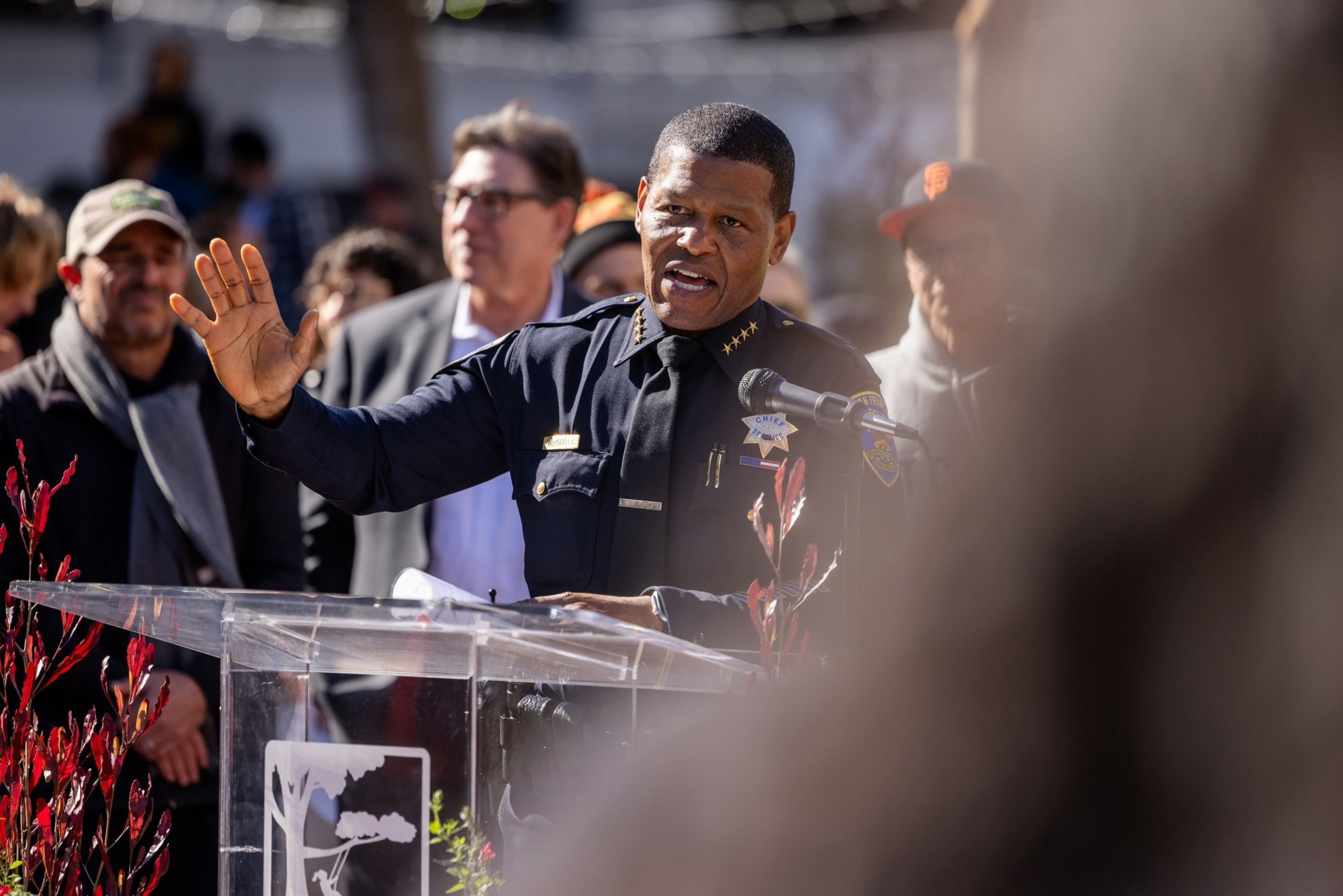 San Francisco Police Department Police Chief Bill Scott, wearing a police uniform holds out his right hand as he gives as speech to a group of people during a press conference to celebrate the reopening of the U.N Plaza which included a skateboard park.