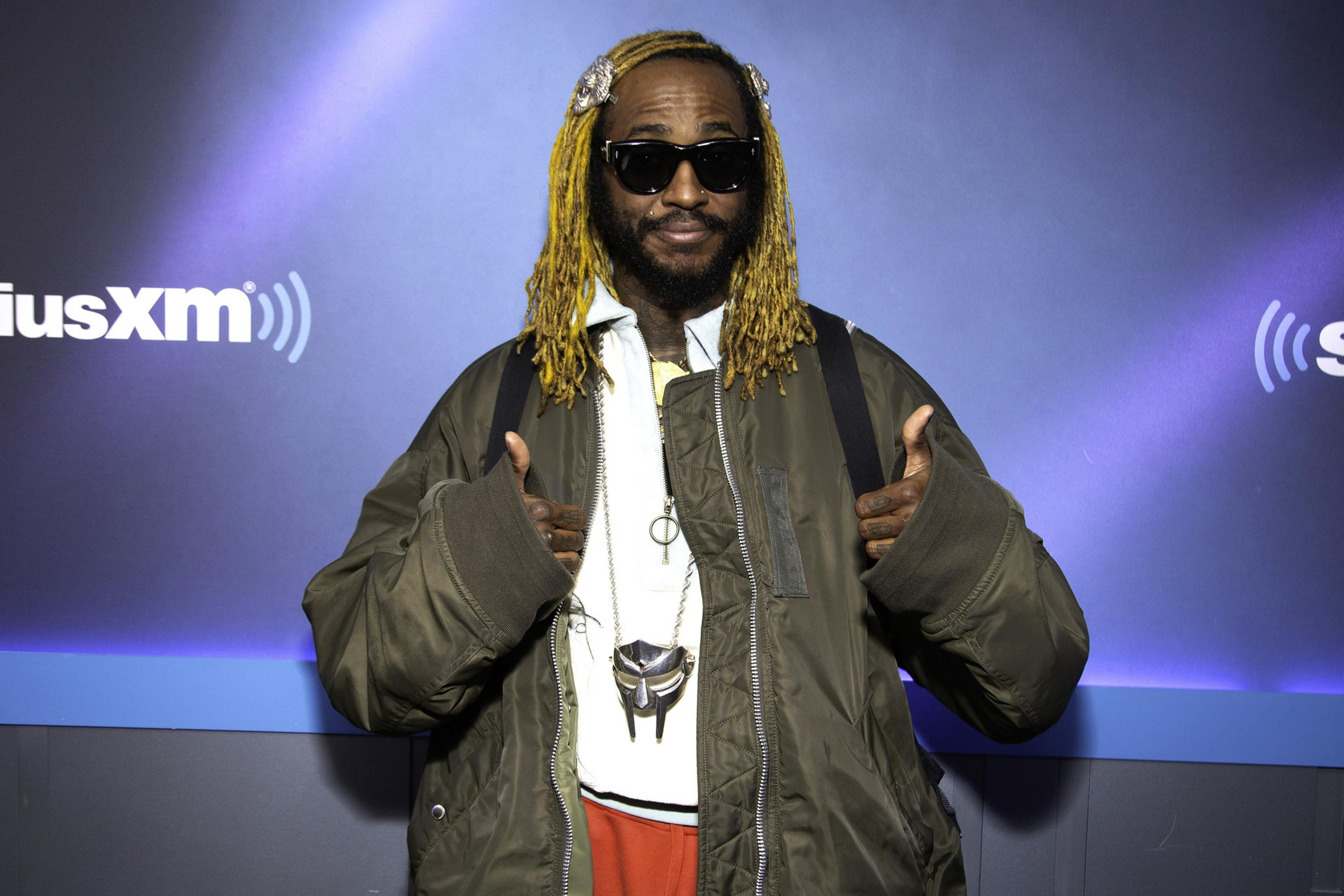 Thundercat in sunglasses and blond hair giving a thumbs up