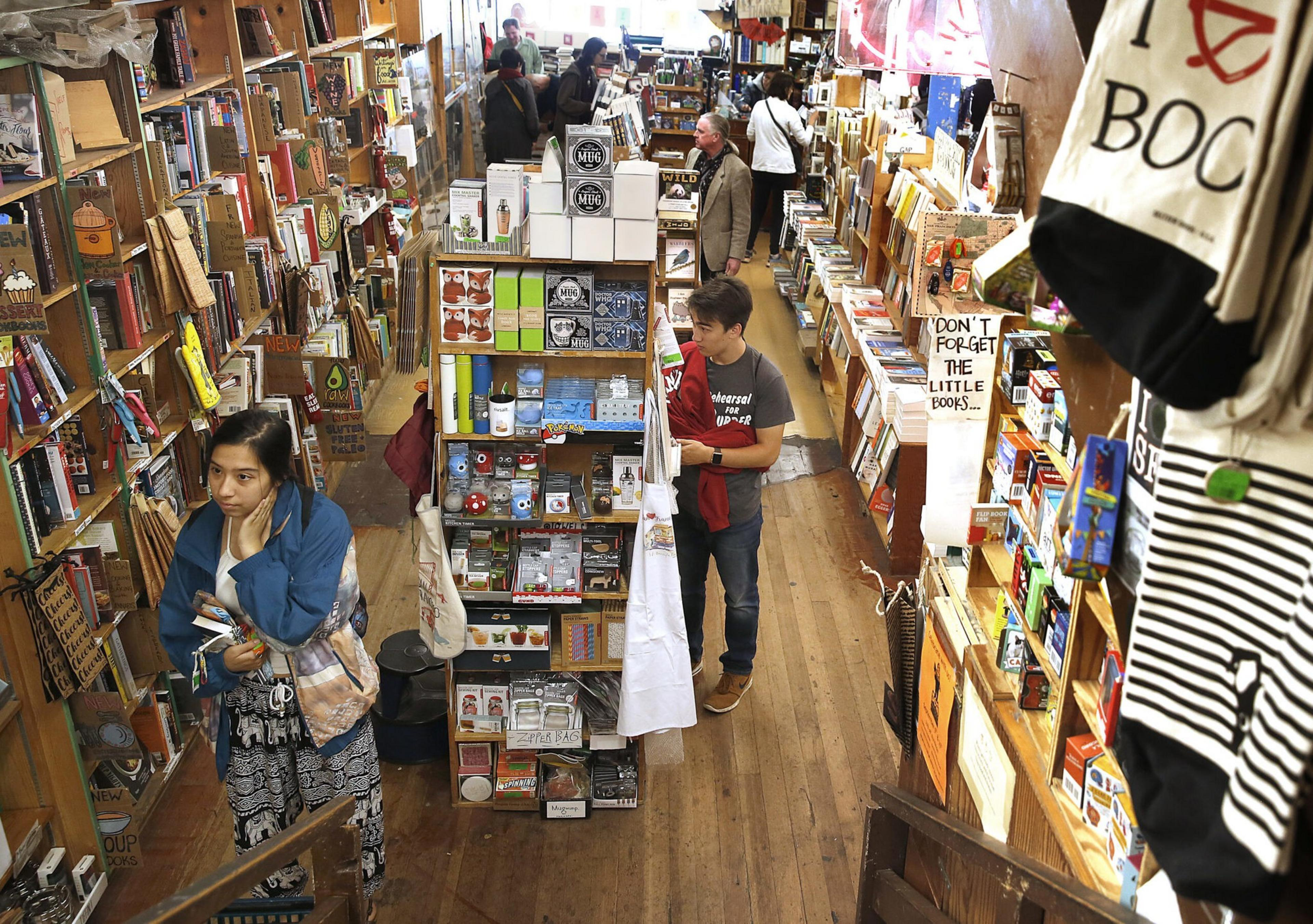 A woman and a boy browse for books in a shop.