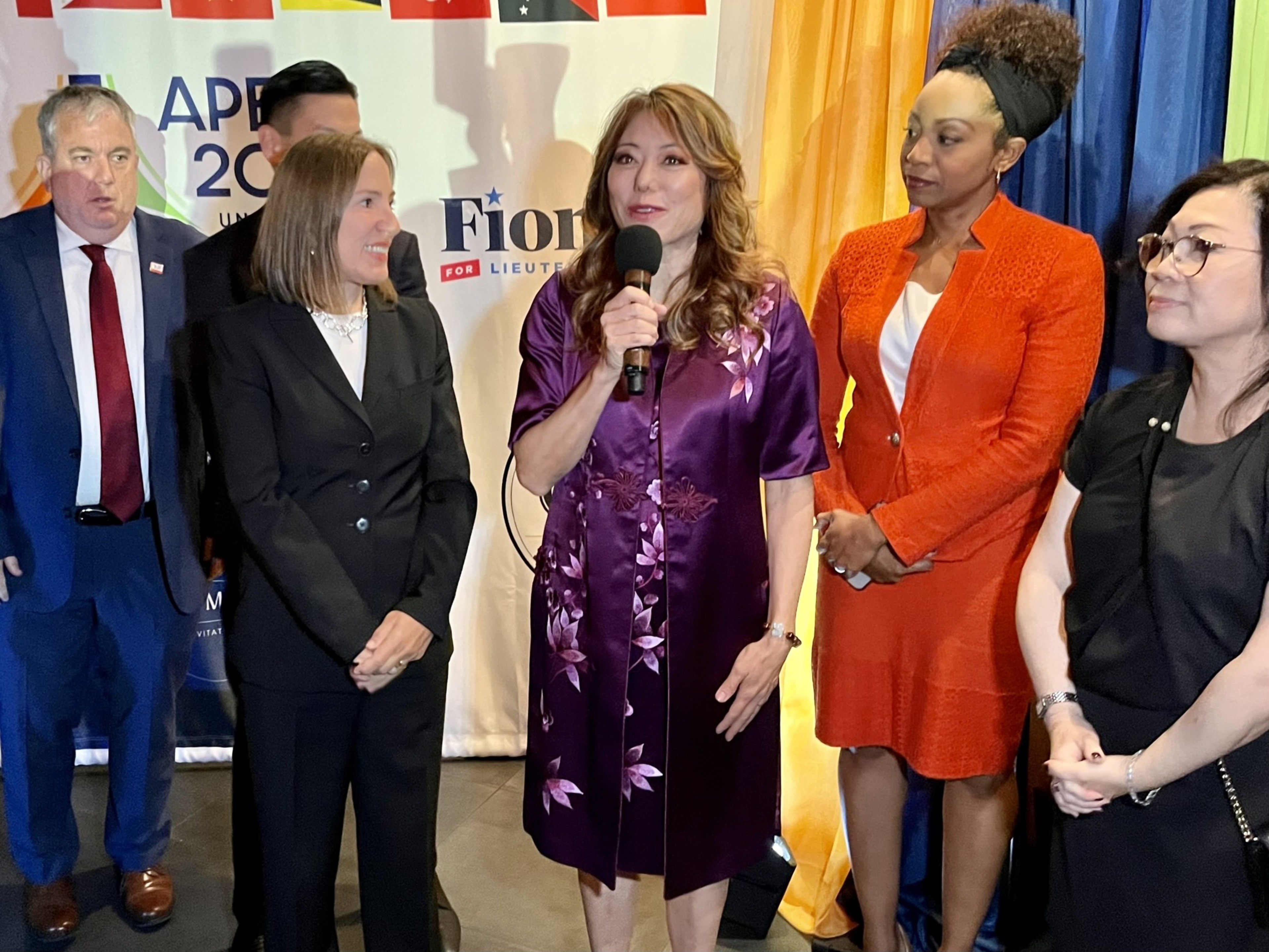 Multiple speakers, including California top officials, gather for a photo at an event.