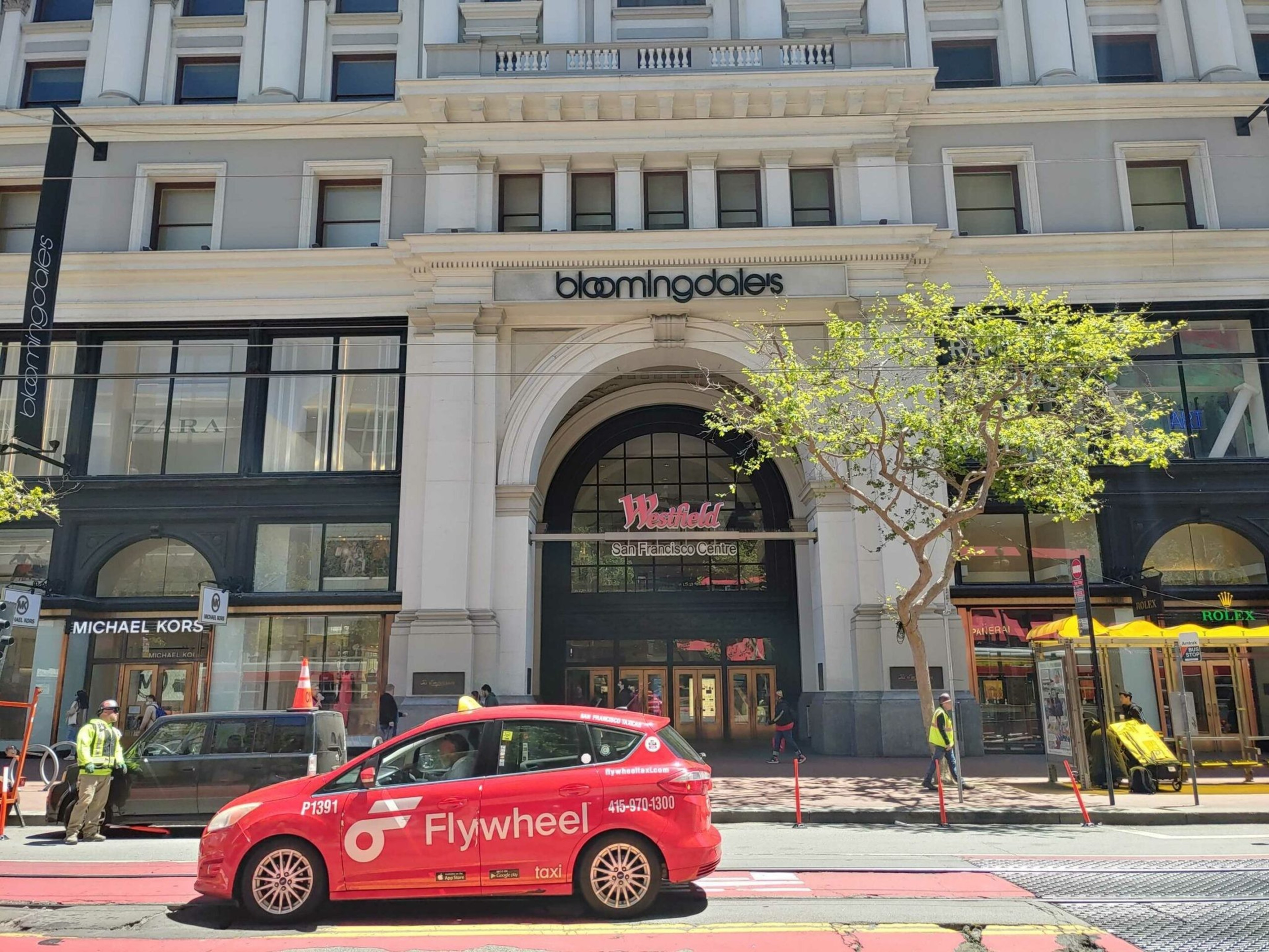 a red car drives past a brick building