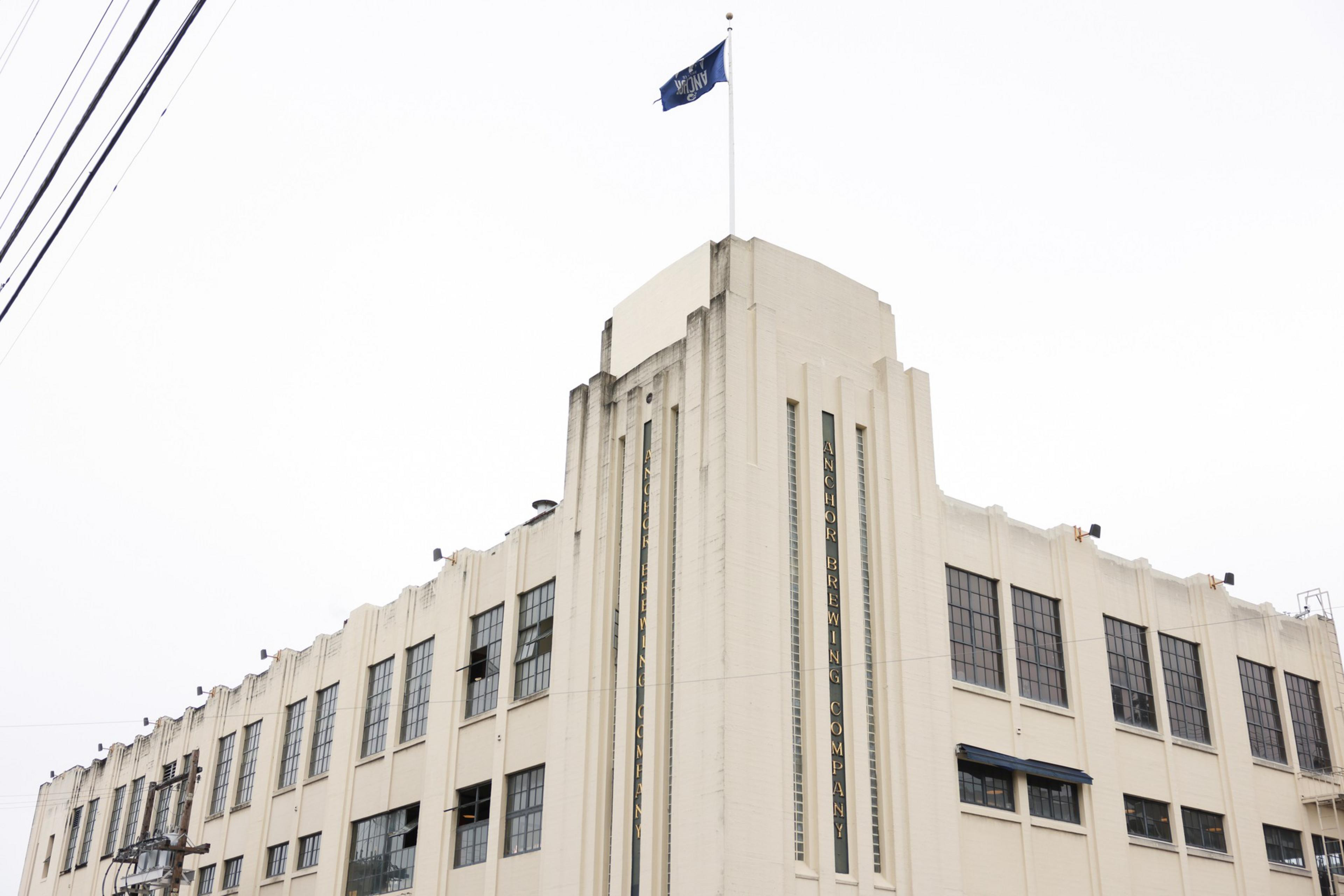 A large beige Art Deco building with many windows and a blue flag on top, labeled "Manchester Company" on the corner.