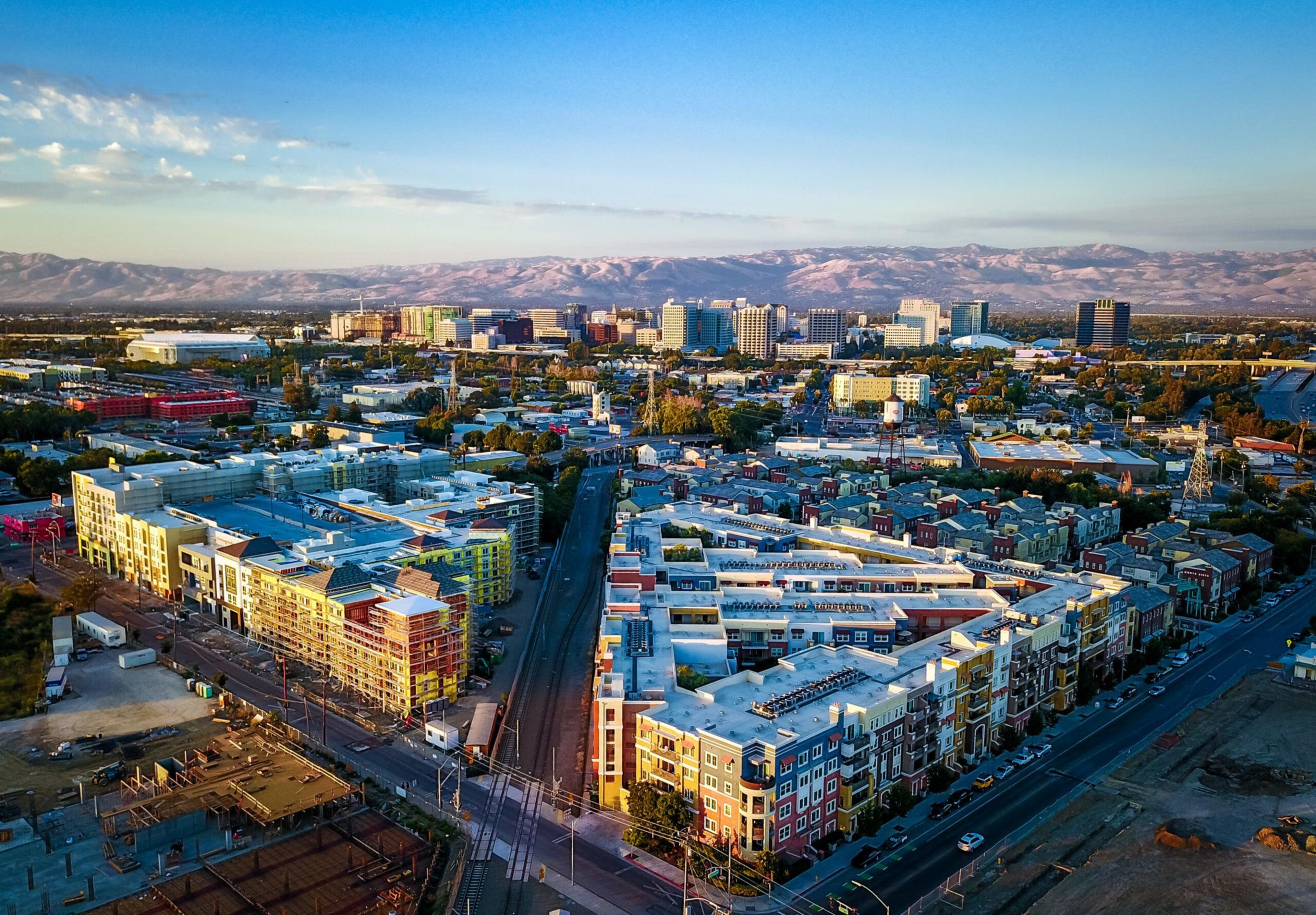 Aerial view of a colorful urban landscape at sunset with mountains in the background.