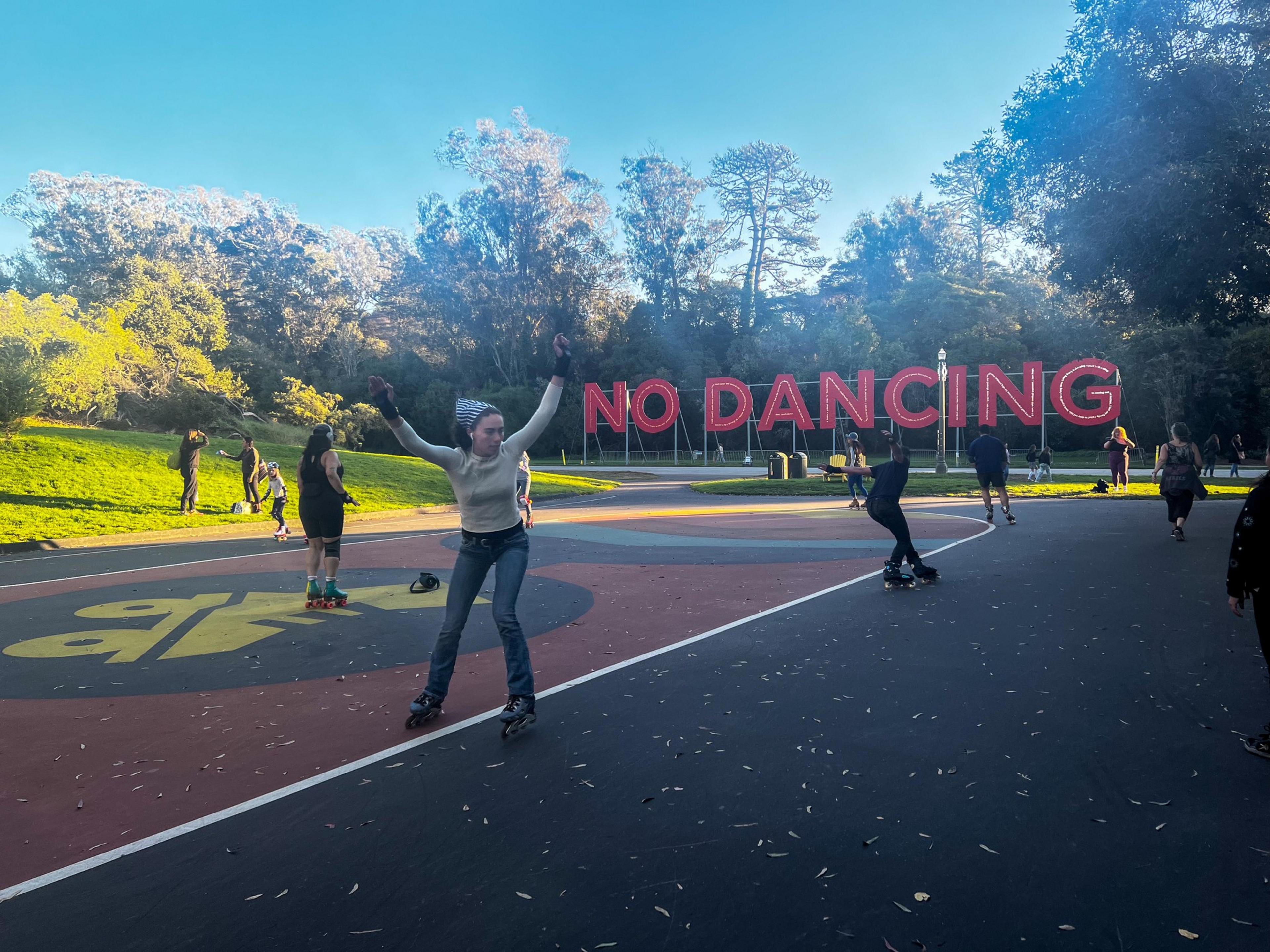 People roller skate with a big red sign that reads &quot;No Dancing&quot;