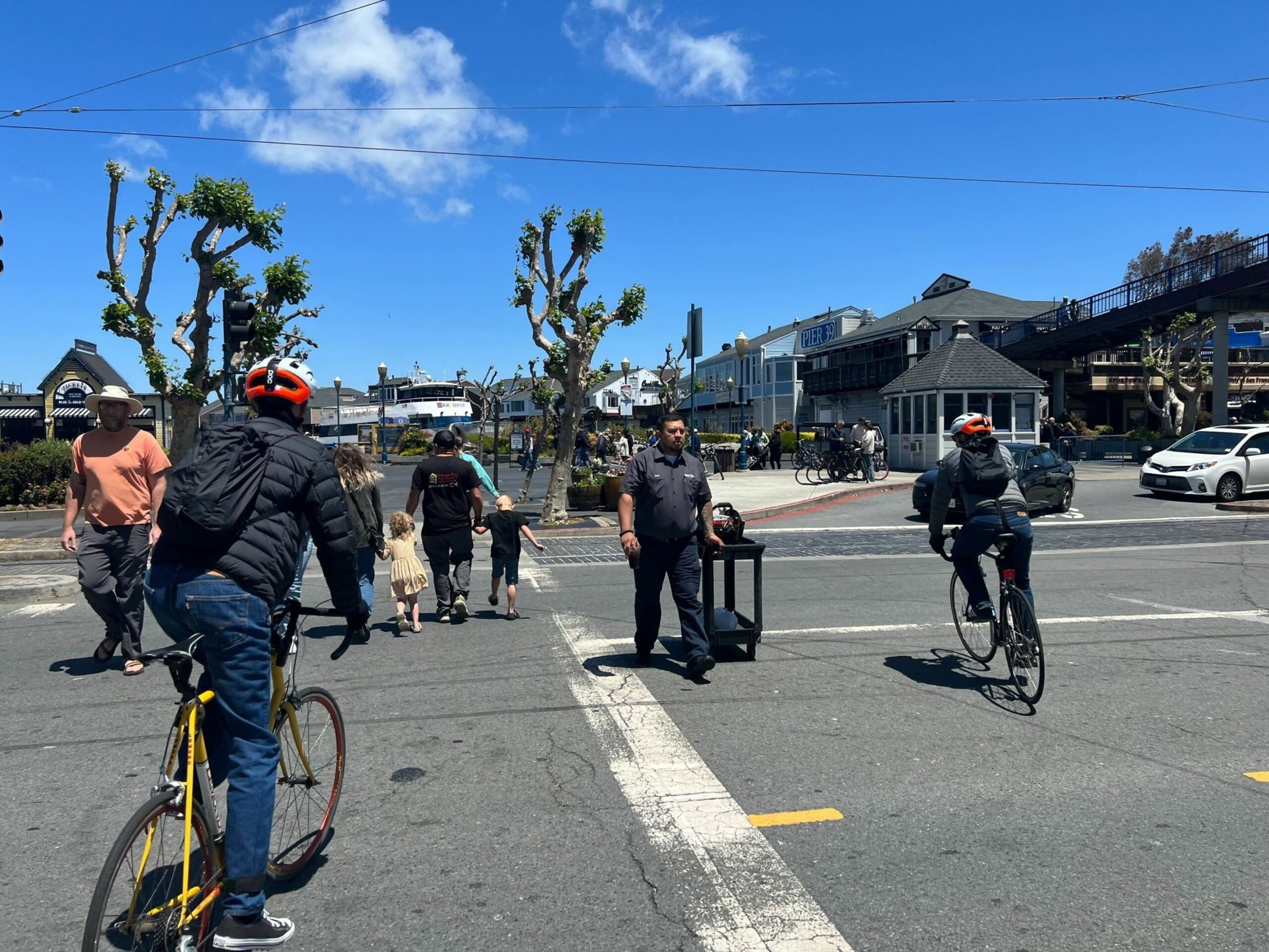 Pedestrians and motorists move along Embarcadero on Monday, near the scene of a car-to-car shooting that injured six on Father's Day. | Julie Zigoris/The Standard