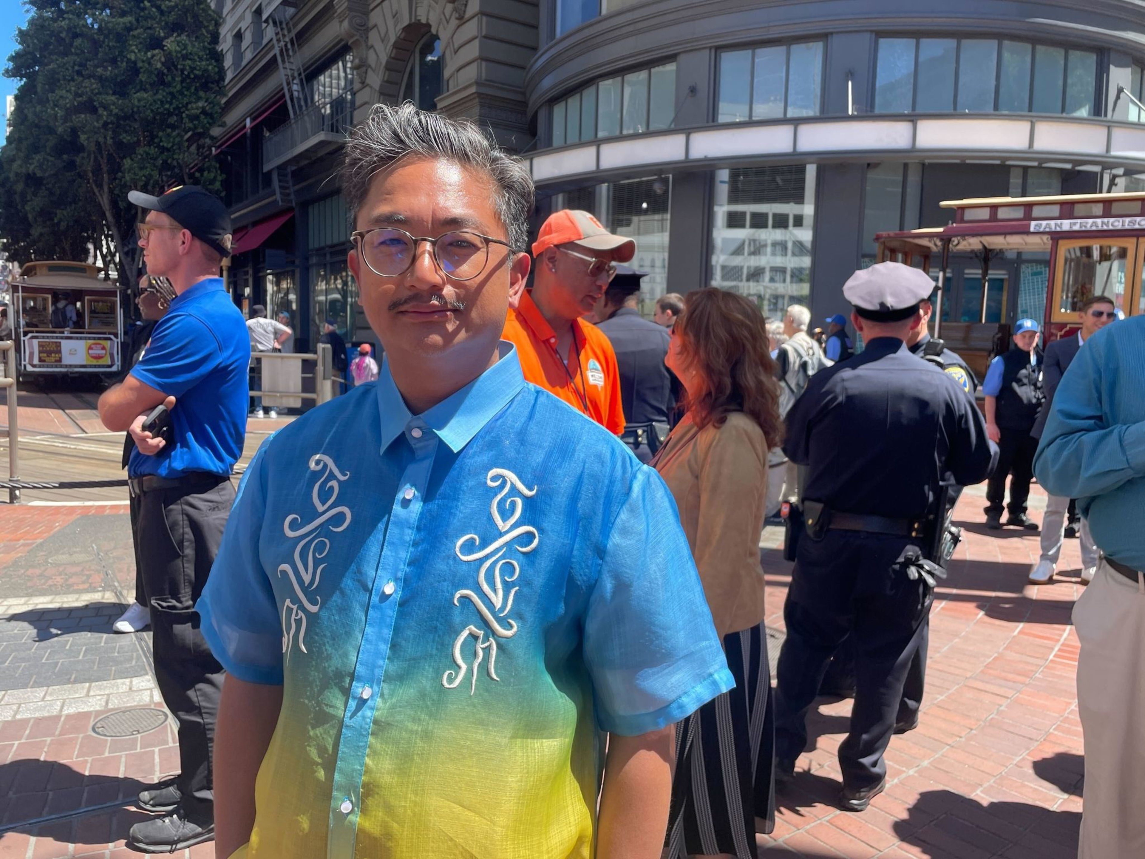 A man with a blue and yellow shirt looks into the camera.