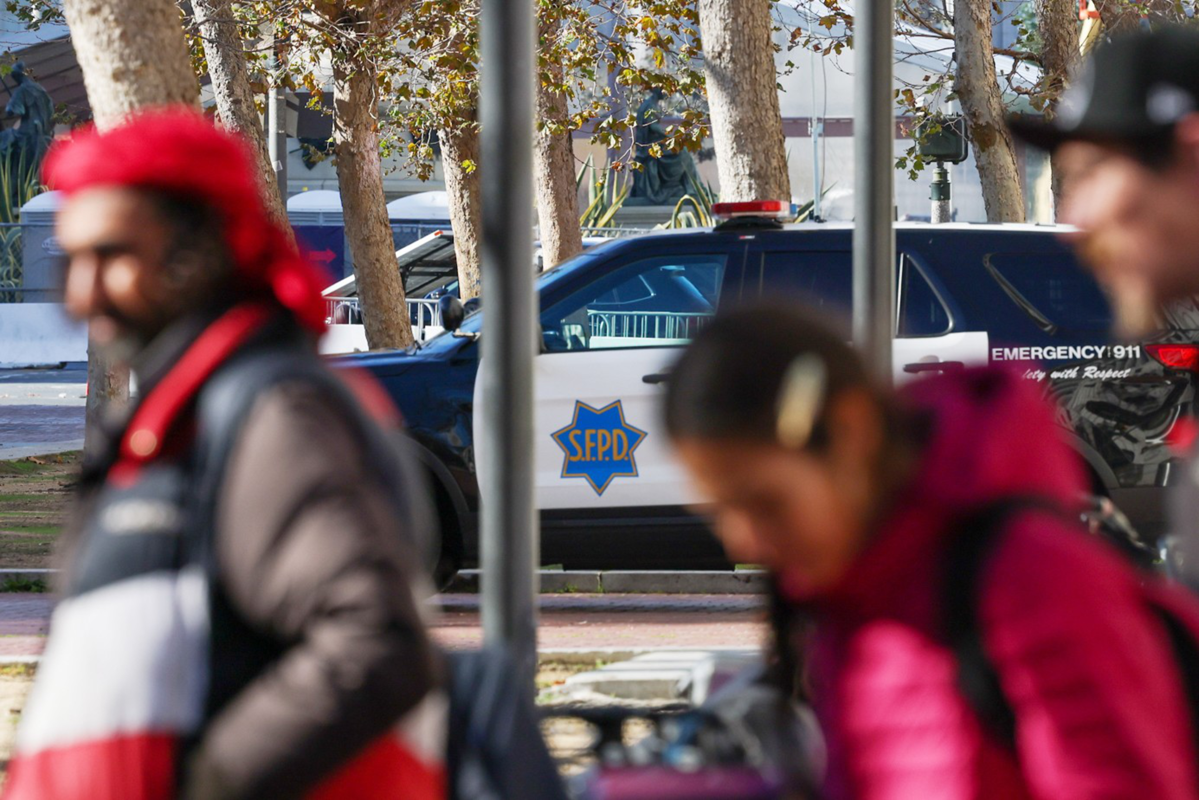 People walk on Market Street as a police vehicle goes by