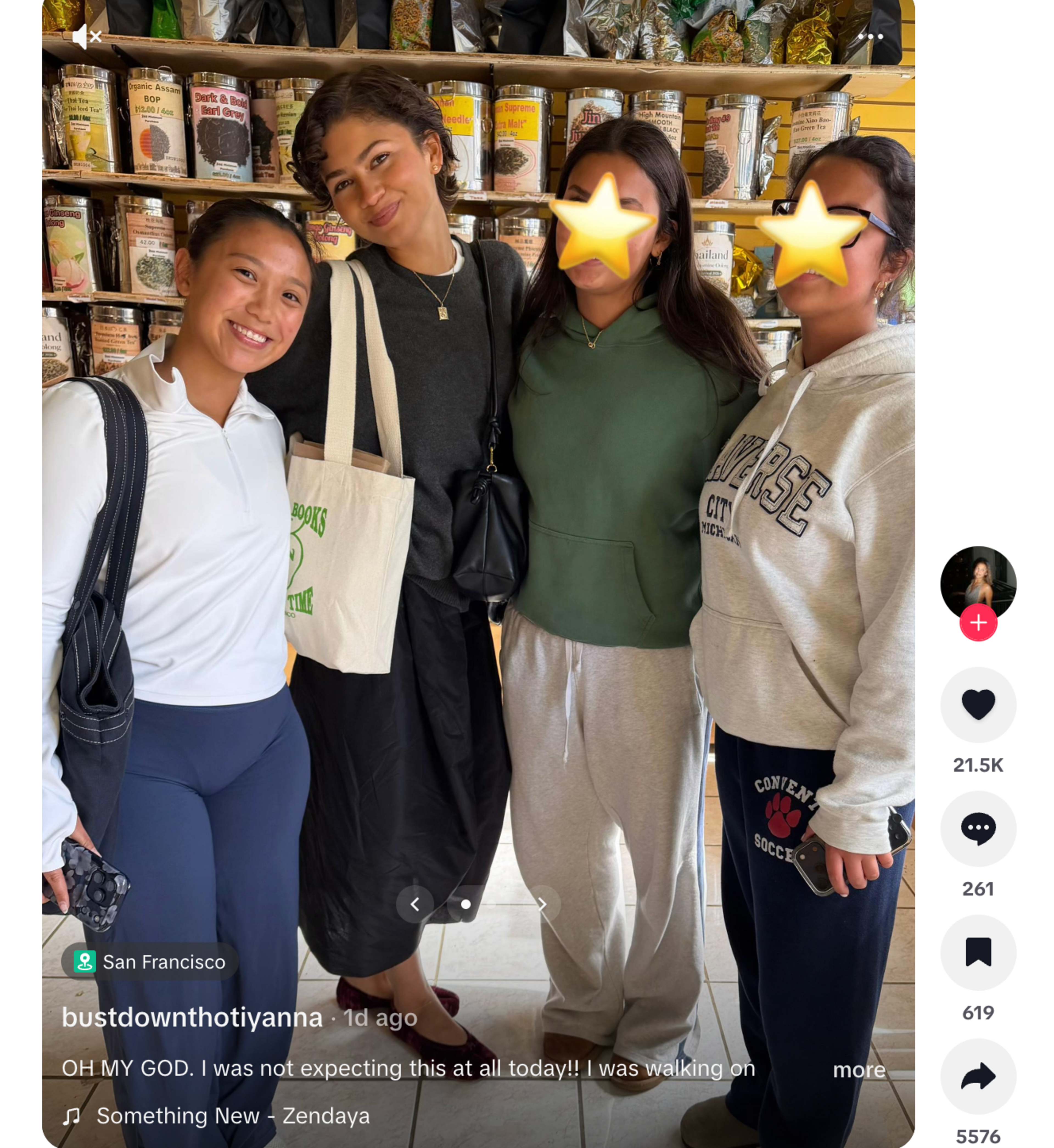 Four young women stand closely together inside a shop, smiling in front of shelves filled with various metal tins and colorful packaging.