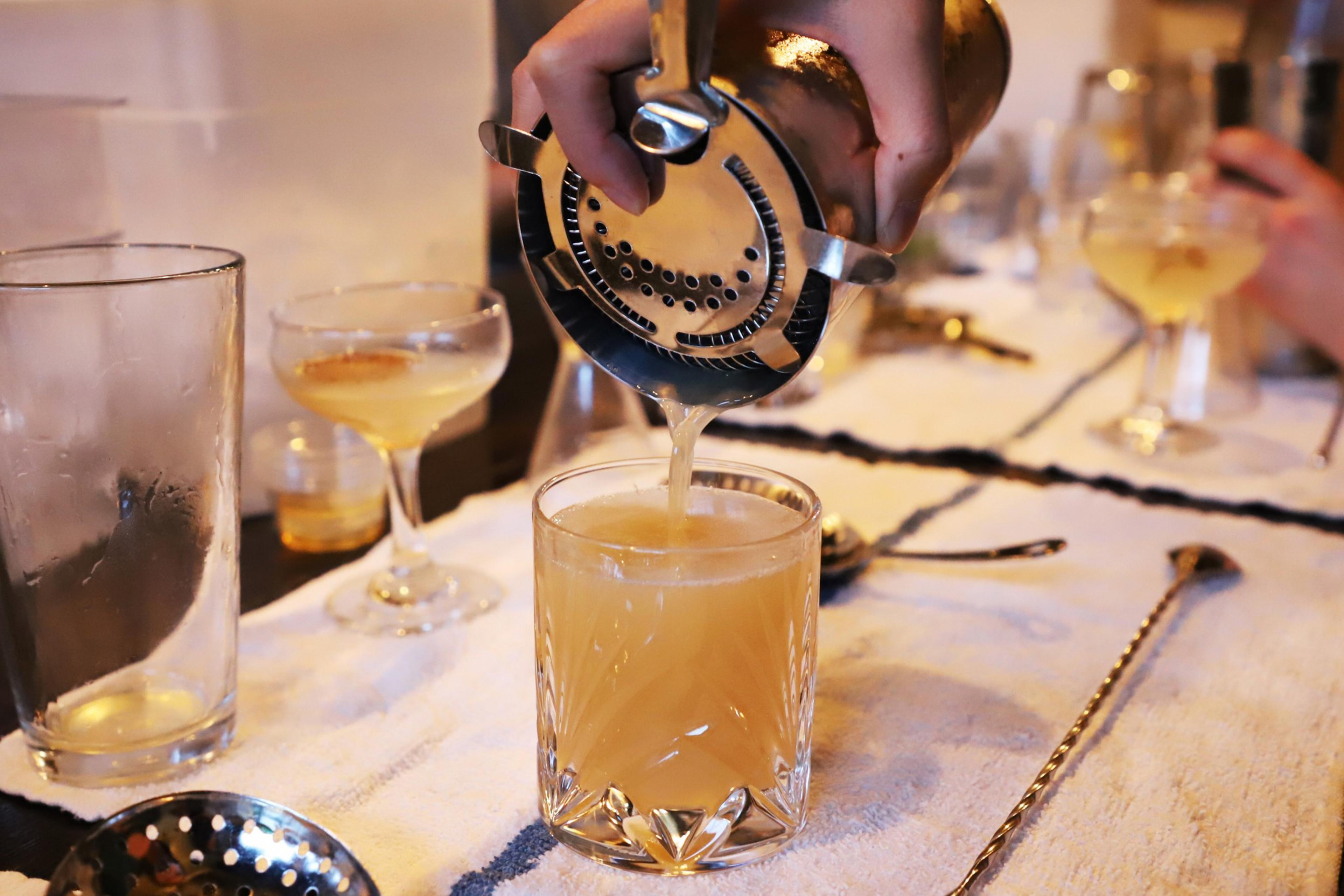 A bartender pours a cocktail from a shaker.