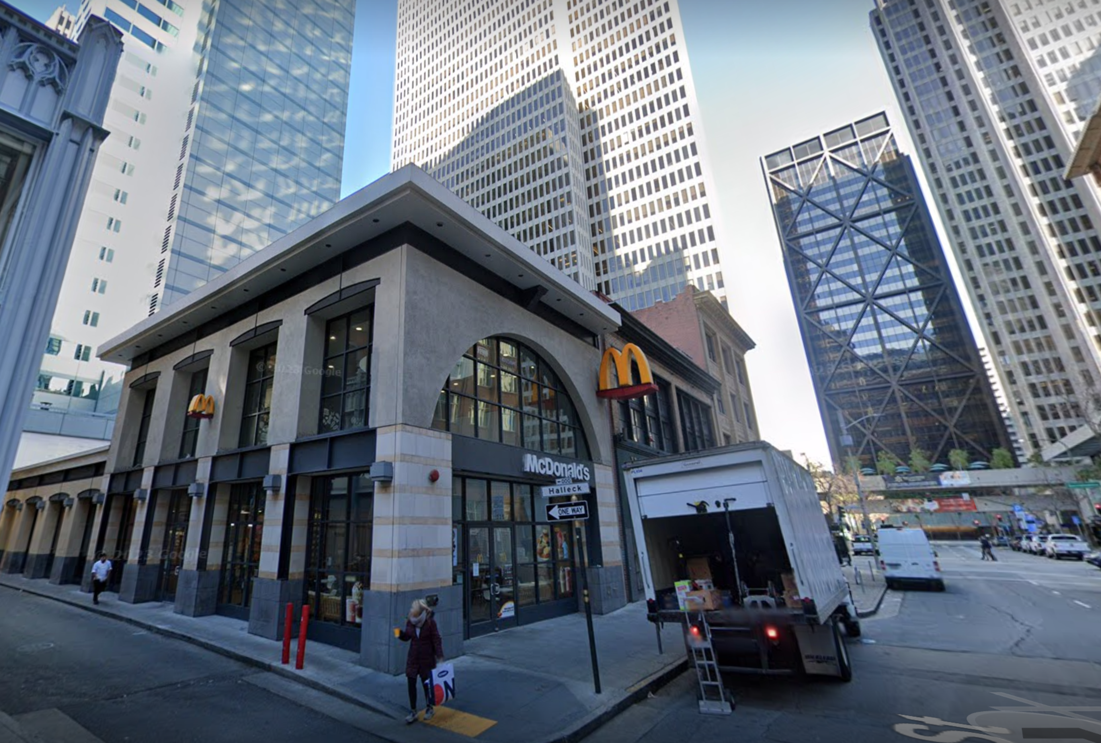 A McDonald's restaurant in a cityscape with tall buildings and a blue sky.