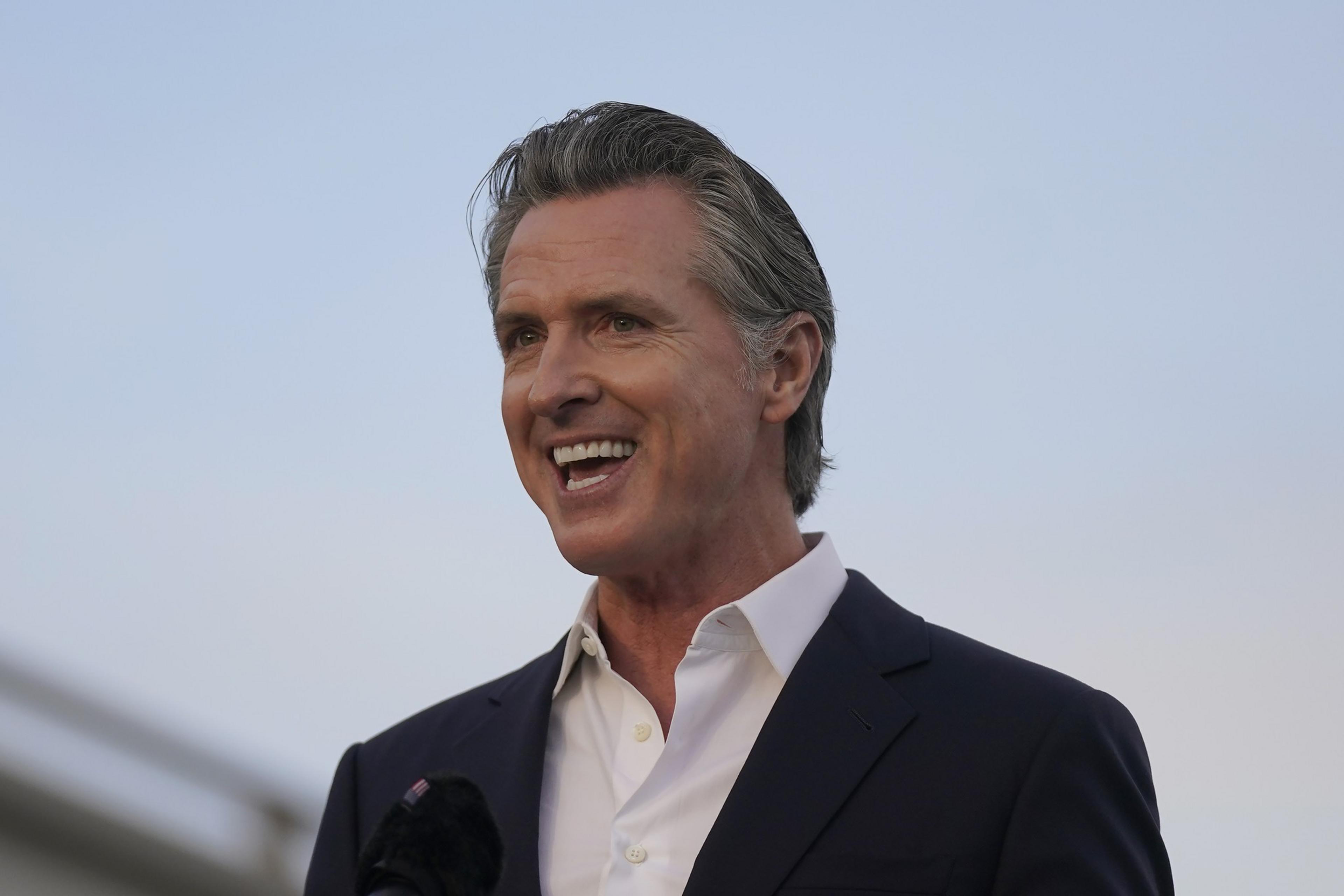 Gray haired man in white collared shirt and blazer smiles